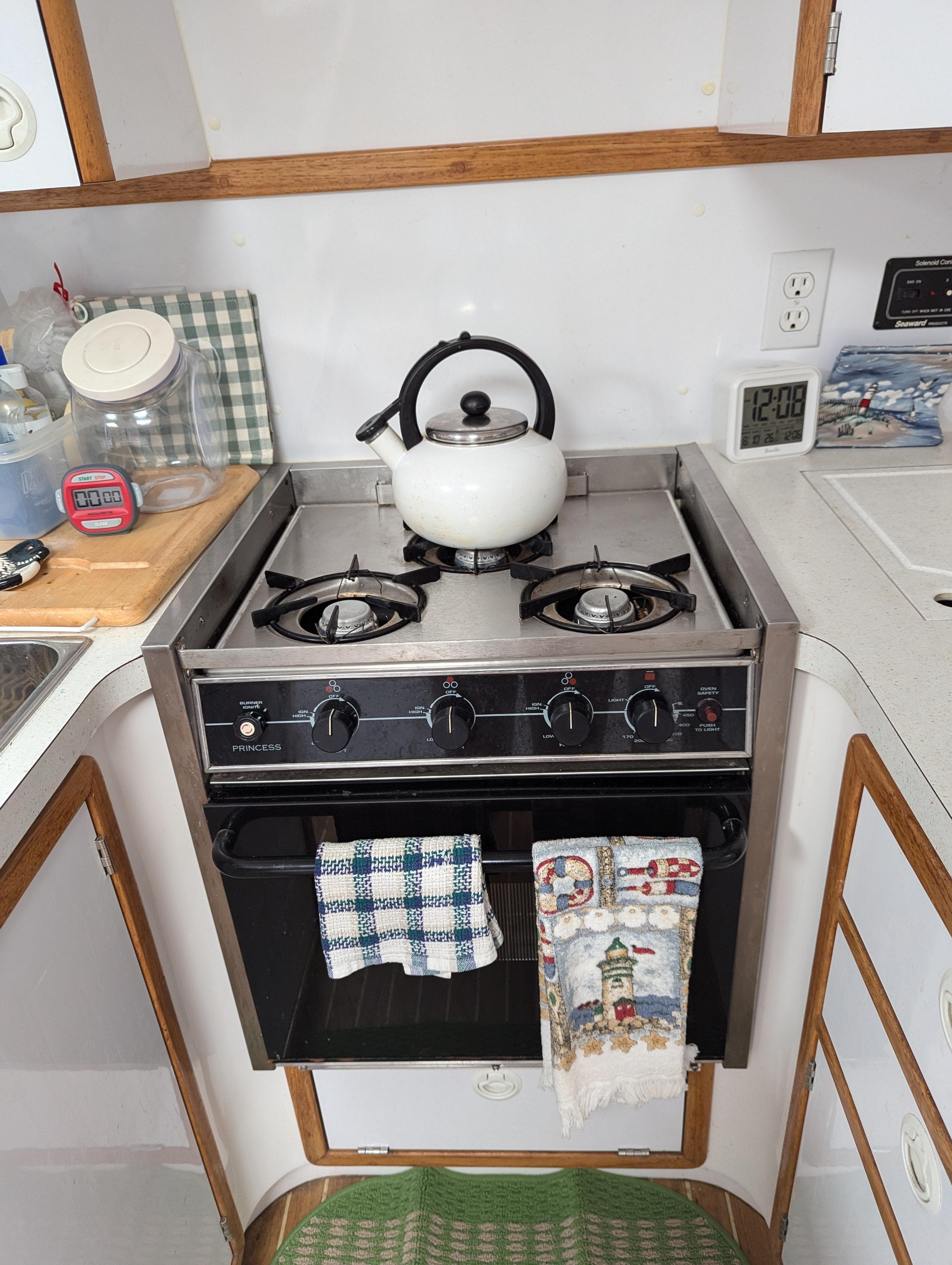 Compact kitchen with a gas stove, kettle, and towels in a 2000 Manta 42.