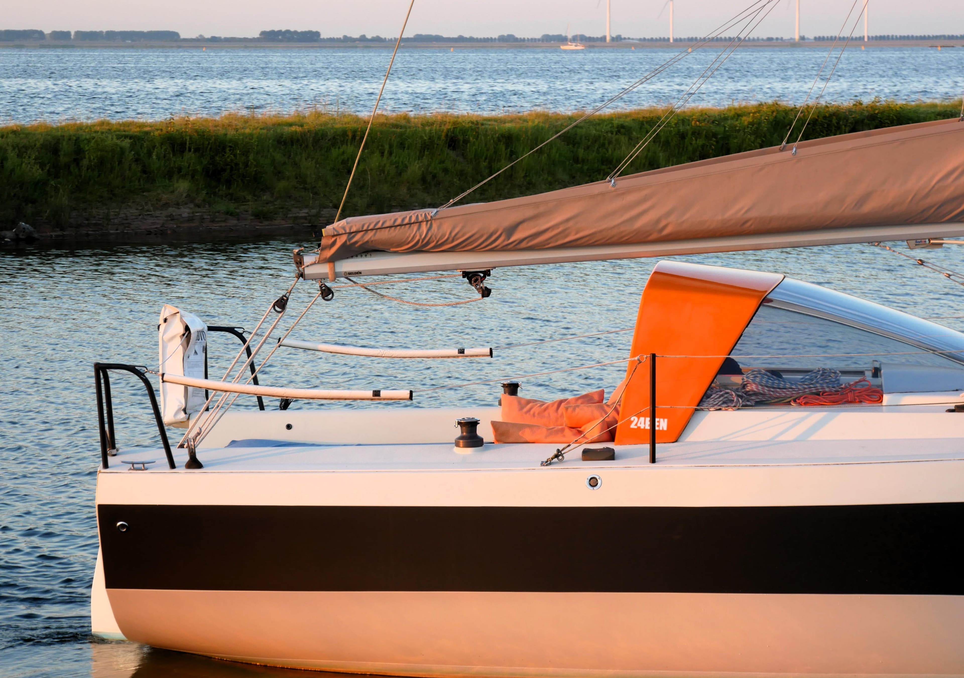 Sailboat Bente 24, 2016 model, docked by a serene lake with lush greenery.