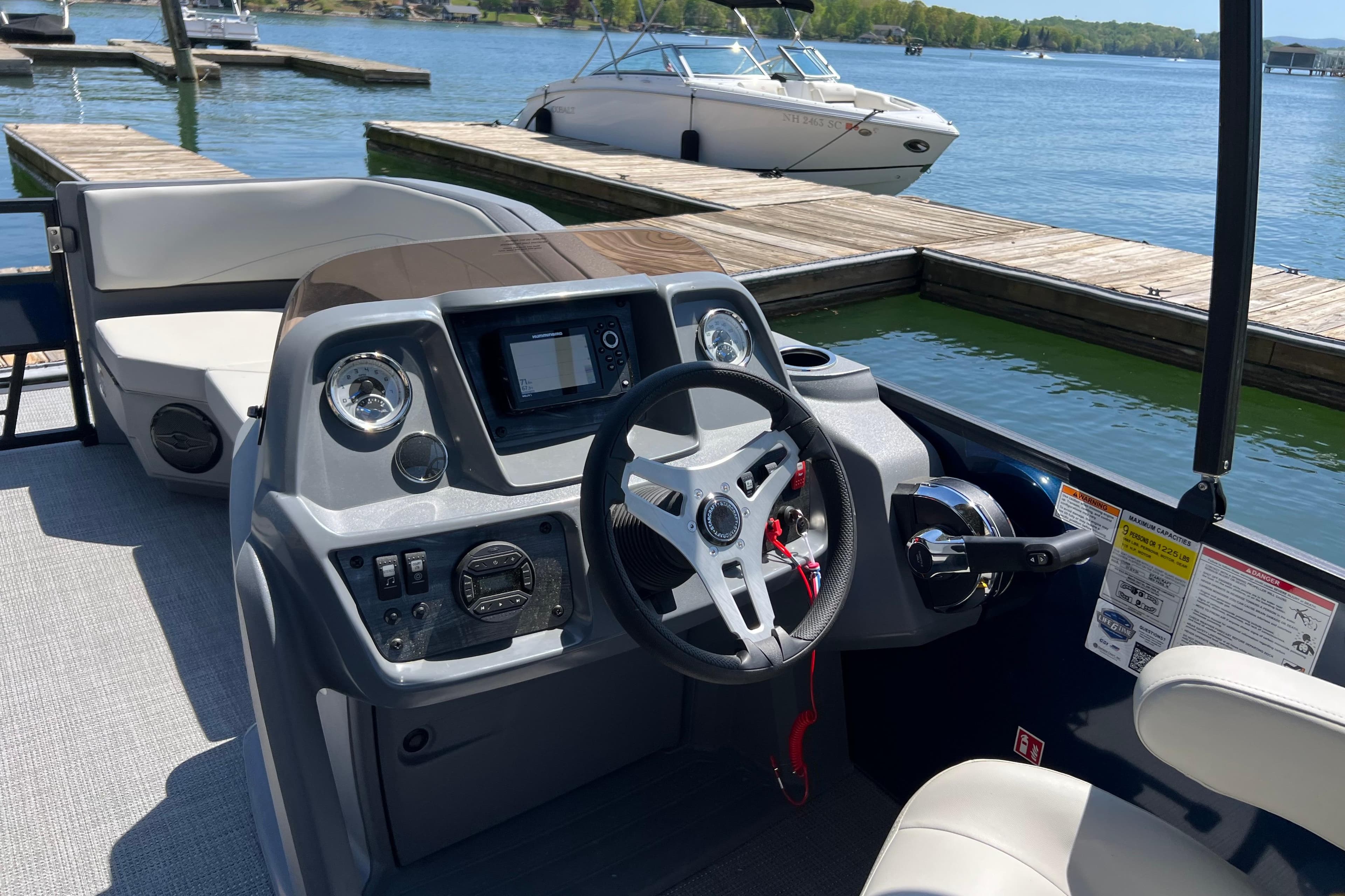 Helm of 2026 Starcraft GX 22 R DH boat at dockside, featuring modern controls and steering.