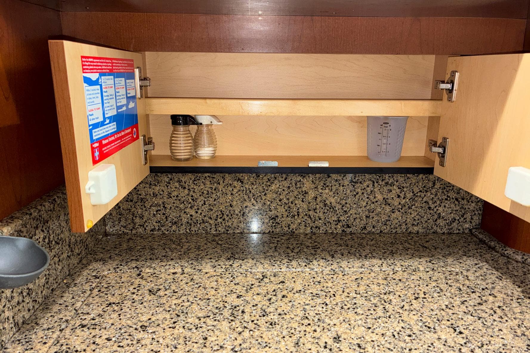Open cabinet on 2007 Sea Ray 44 Sedan Bridge with granite countertop and spice containers.
