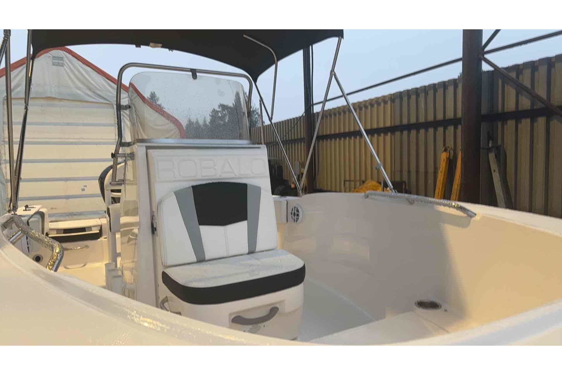 2023 Robalo R180 Center Console boat with seating and canopy in storage.