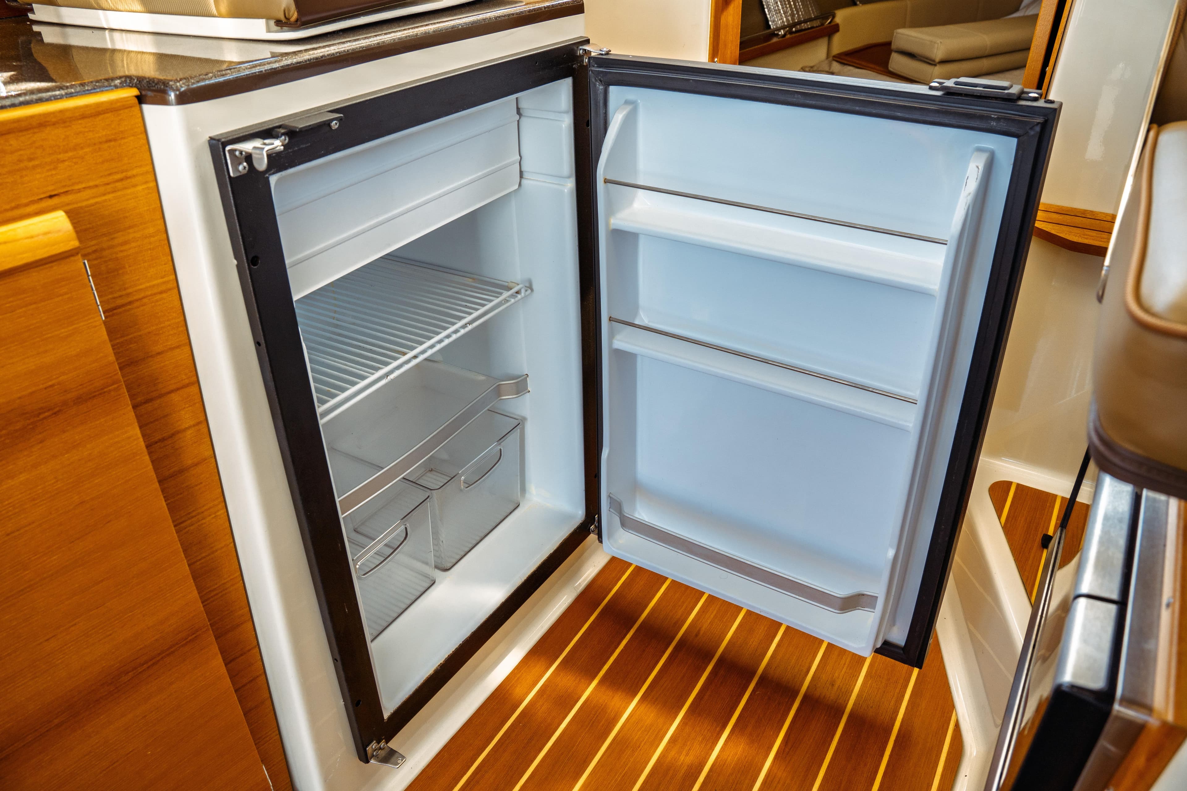 Open refrigerator in 2022 Ranger Tugs R-29 S boat interior, showcasing storage space.
