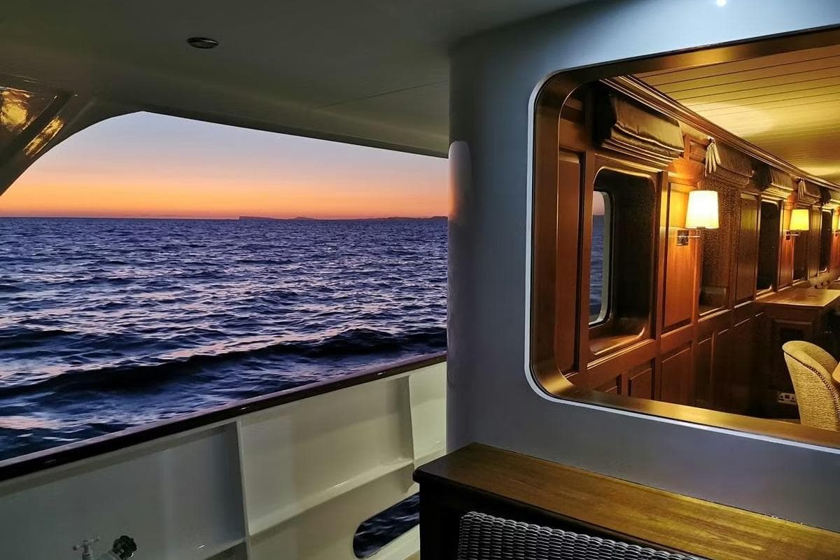 Luxurious 1975 Custom 39M yacht interior with ocean sunset view.