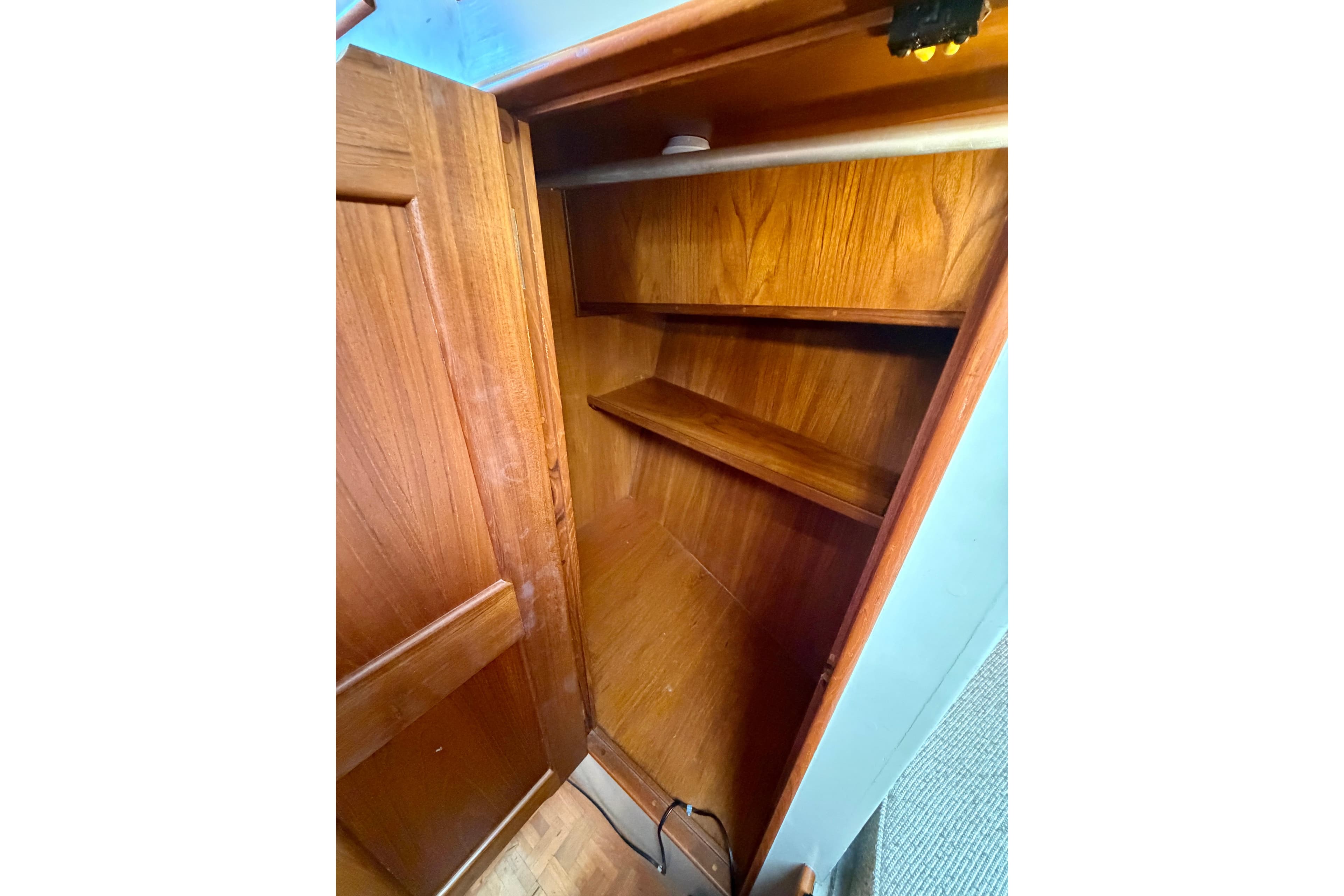 Wooden storage closet inside 1981 Grand Banks 32 Sedan boat, featuring shelves and hanging rod.