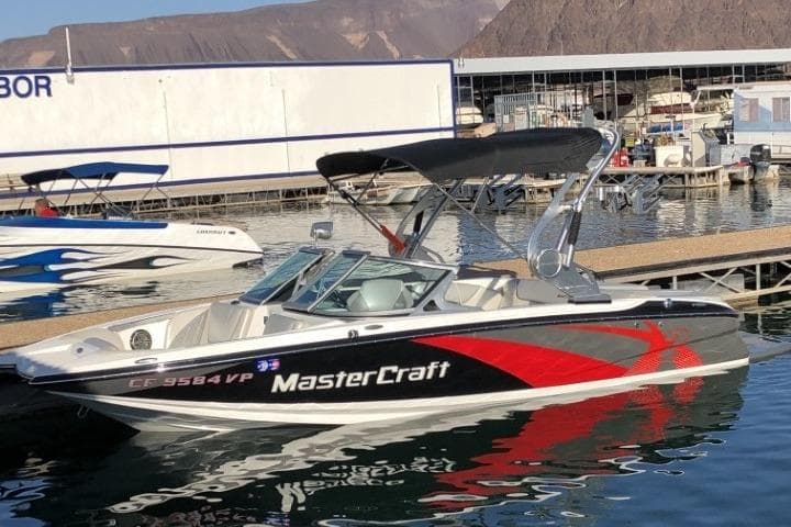 2013 MasterCraft X-2 boat docked at a marina with mountains in the background.