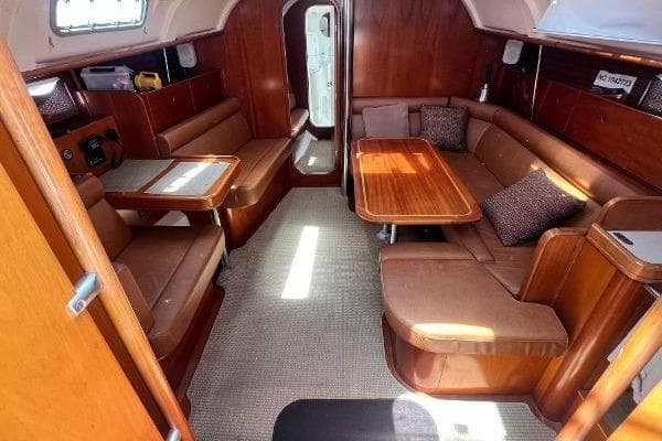 Interior of 1996 Beneteau Oceanis 400 yacht with wooden furnishings and cozy seating area.