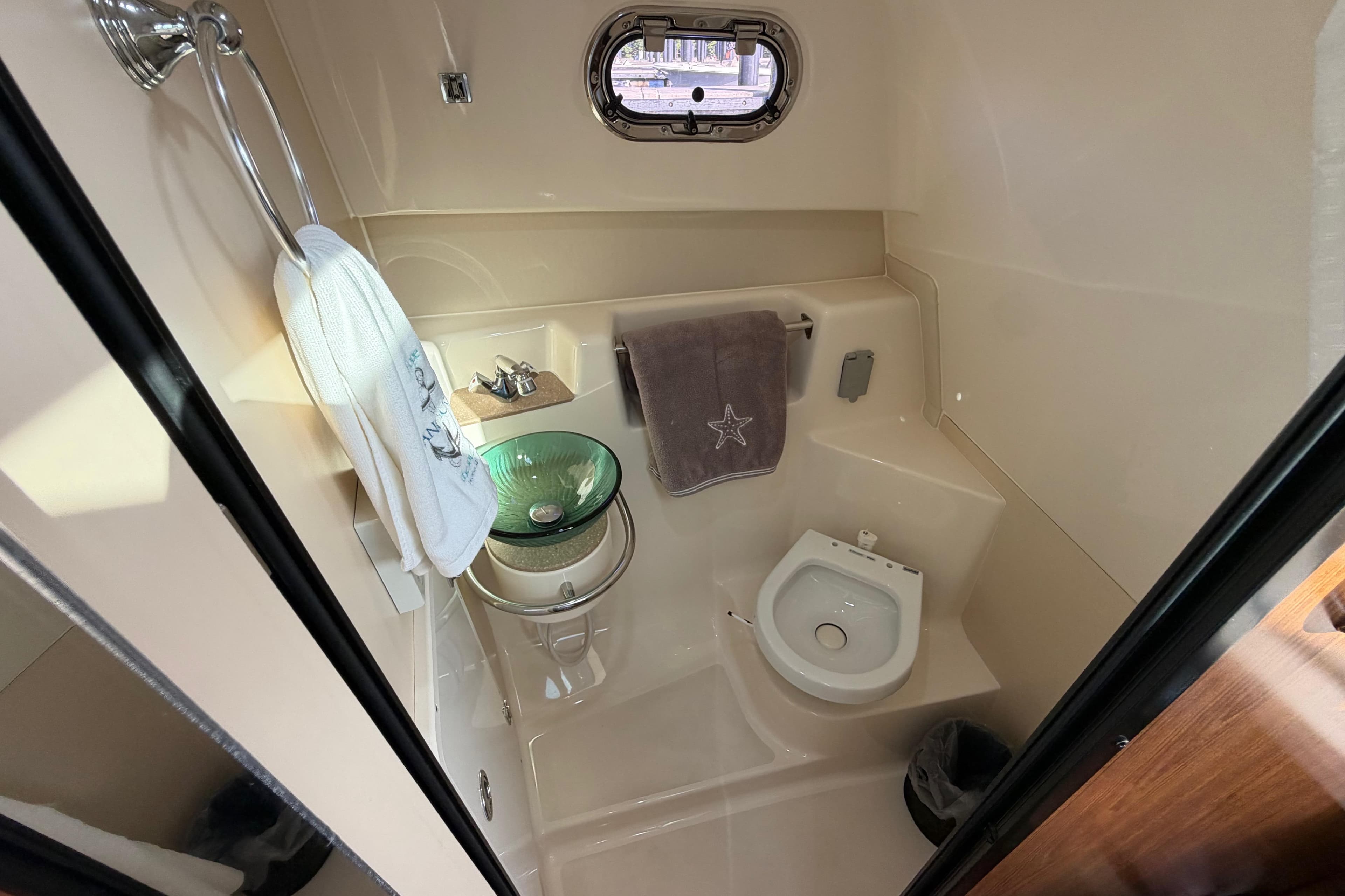 2009 Pursuit OS 315 Offshore boat bathroom with sink, toilet, and porthole window.