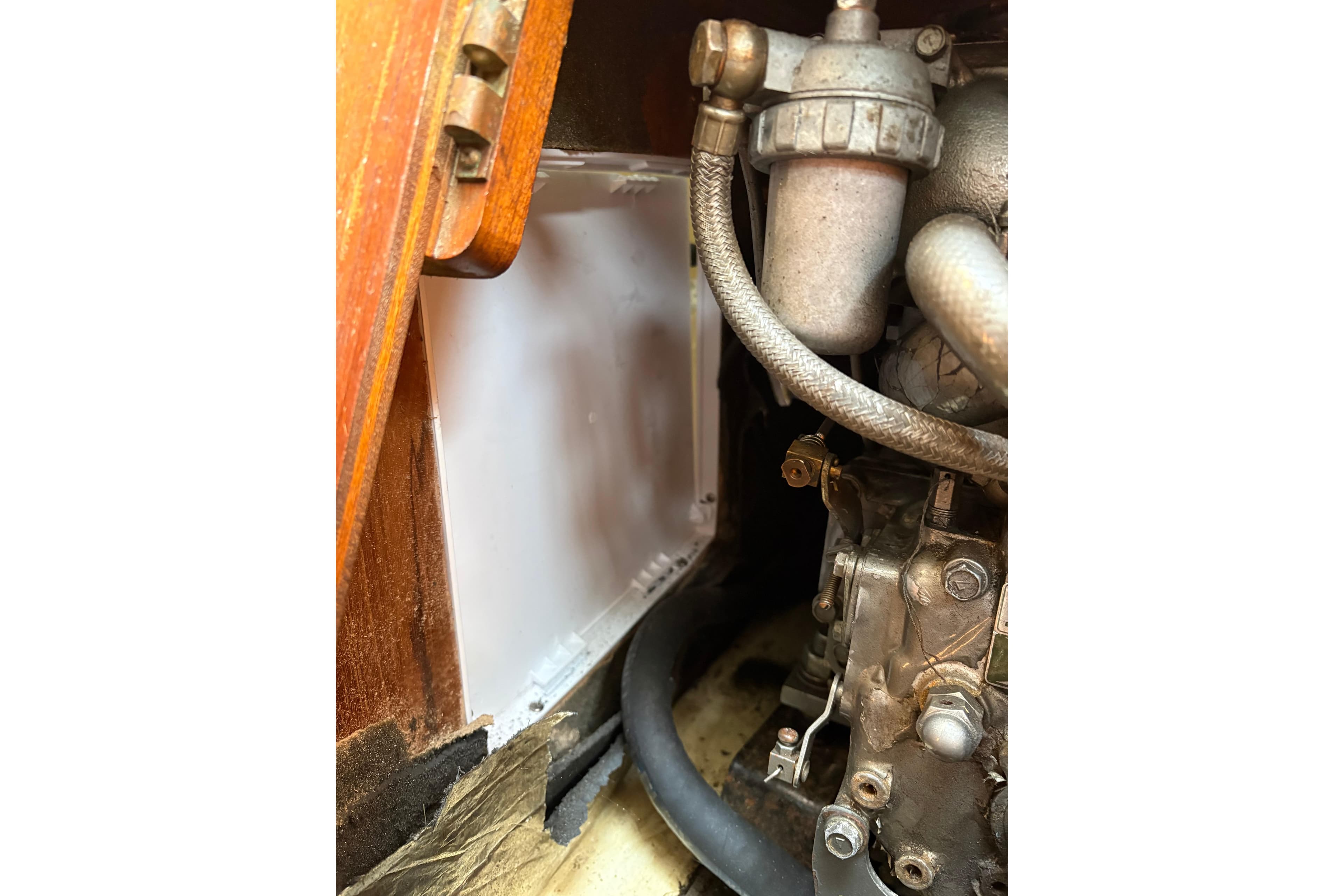 Engine compartment of a 1988 Pearson 28 sailboat, showcasing mechanical components and hoses.