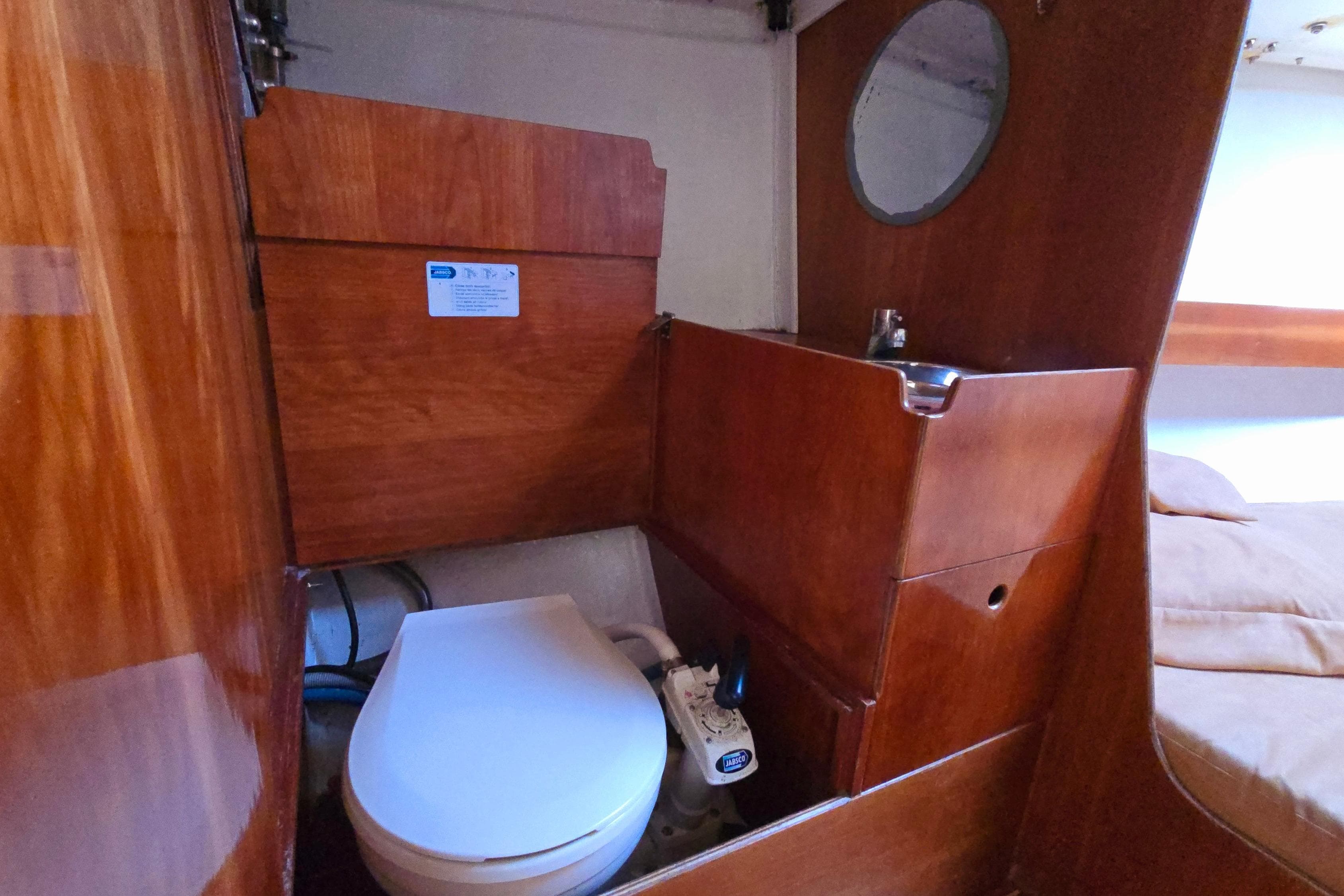 Interior of 2003 FF Boats 1100, featuring a compact wooden bathroom with toilet and sink.