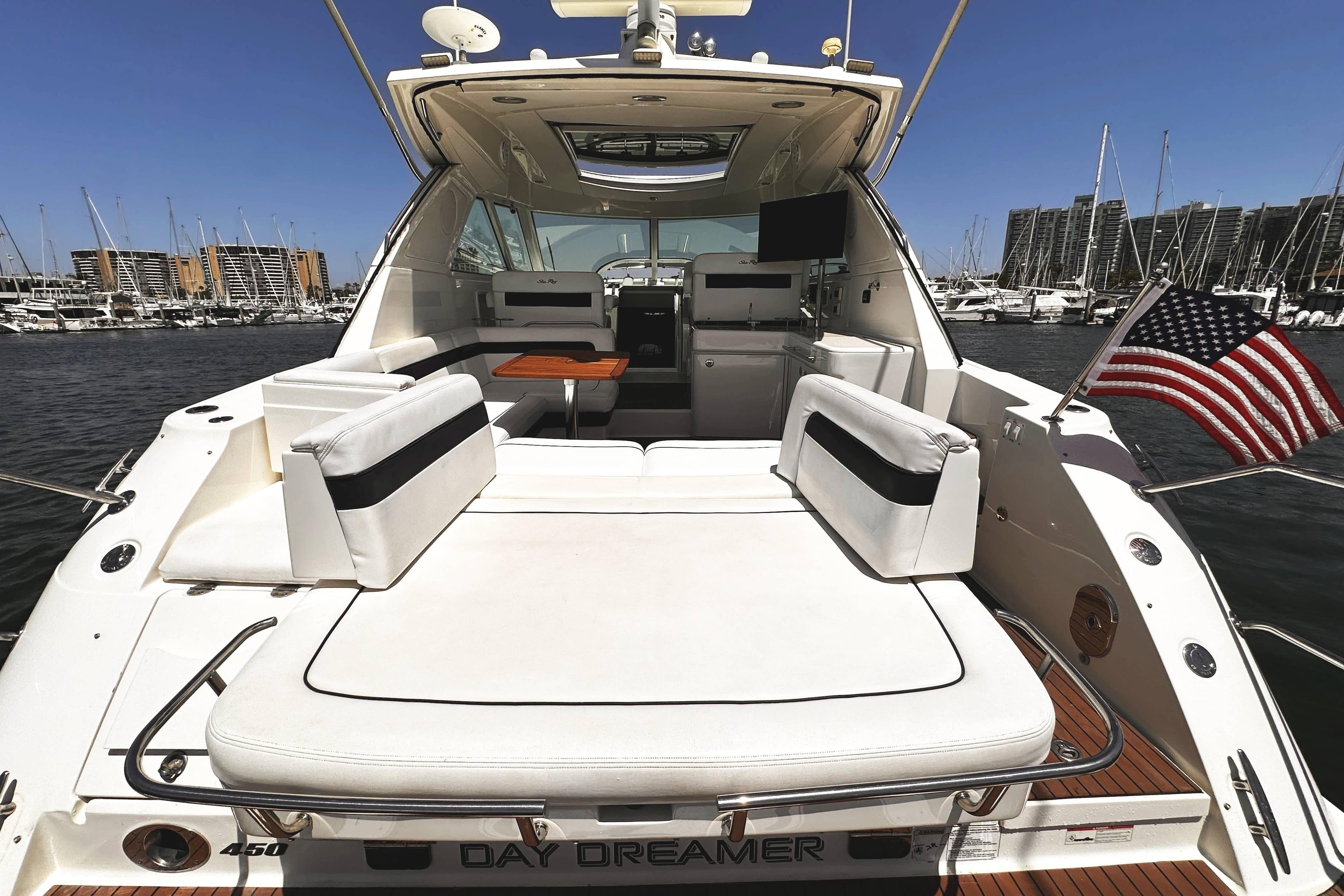 2010 Sea Ray 450 Sundancer yacht with spacious deck, docked in marina, American flag waving.
