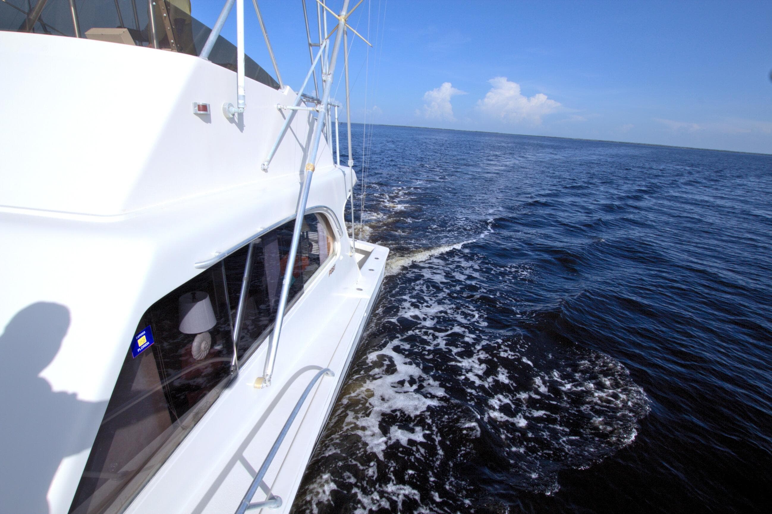 1990 Post 44 Sport Fisherman yacht cruising on open sea under clear blue sky.