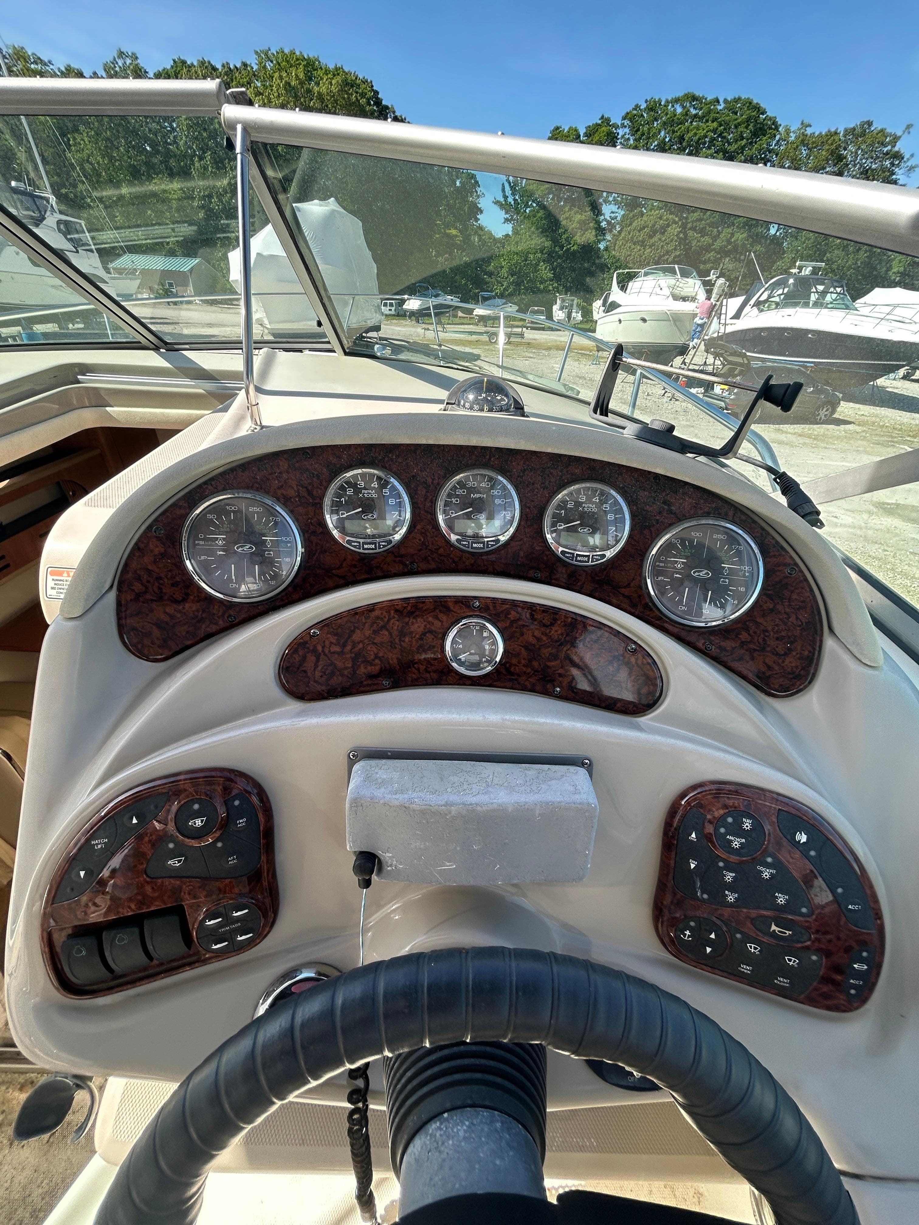 2006 Sea Ray 280 Sundancer dashboard with gauges and controls, docked in a marina.