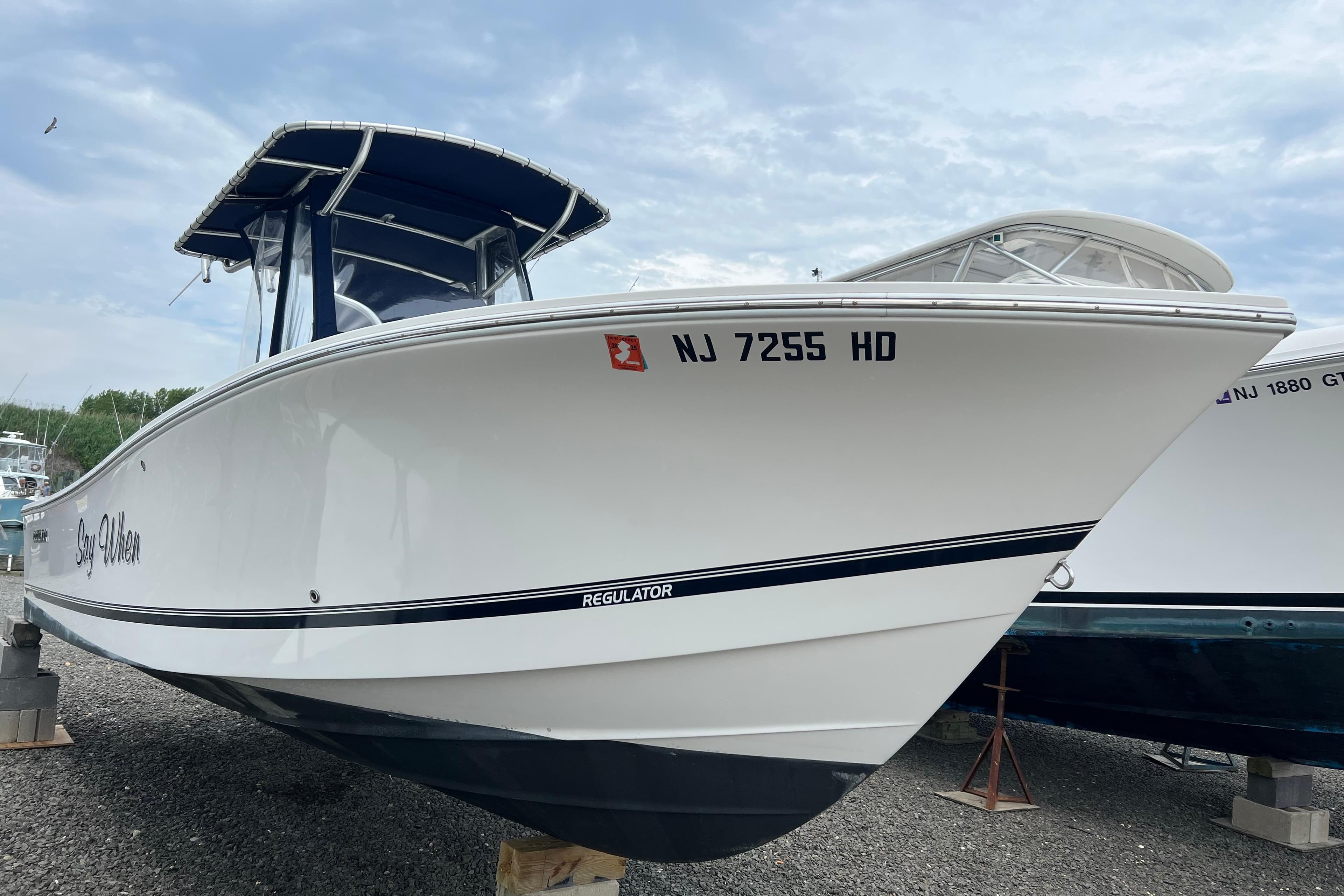 2012 Regulator 23 Forward Seating boat on display, featuring sleek white hull and blue canopy.