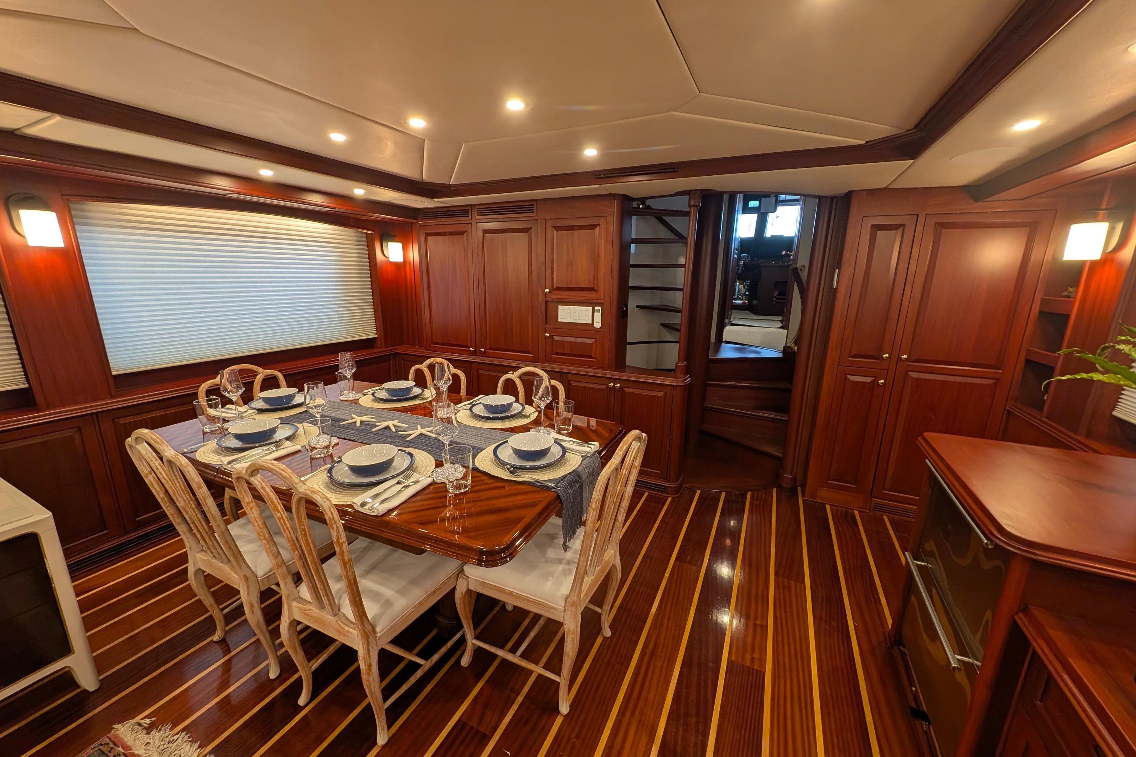 Luxurious yacht dining room with elegant table setting, wooden interiors, and ambient lighting, Doggersbank 2001.