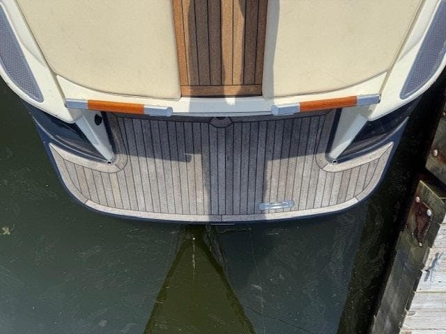 2014 Chris-Craft Launch 25 boat stern with wooden deck, docked on water.