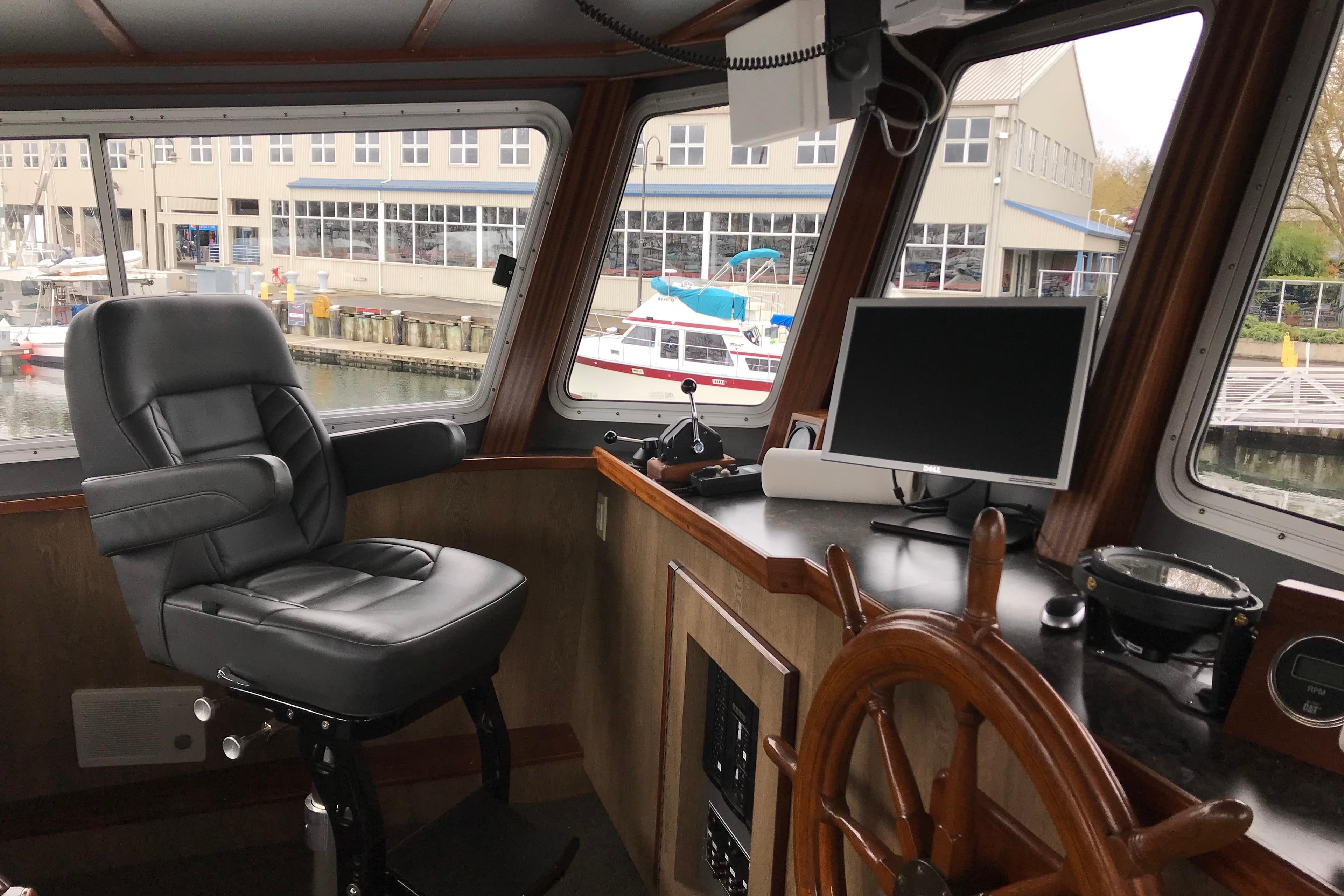 Interior of 1973 Custom 58’ Steel Marco Seiner with helm, chair, and navigation equipment.