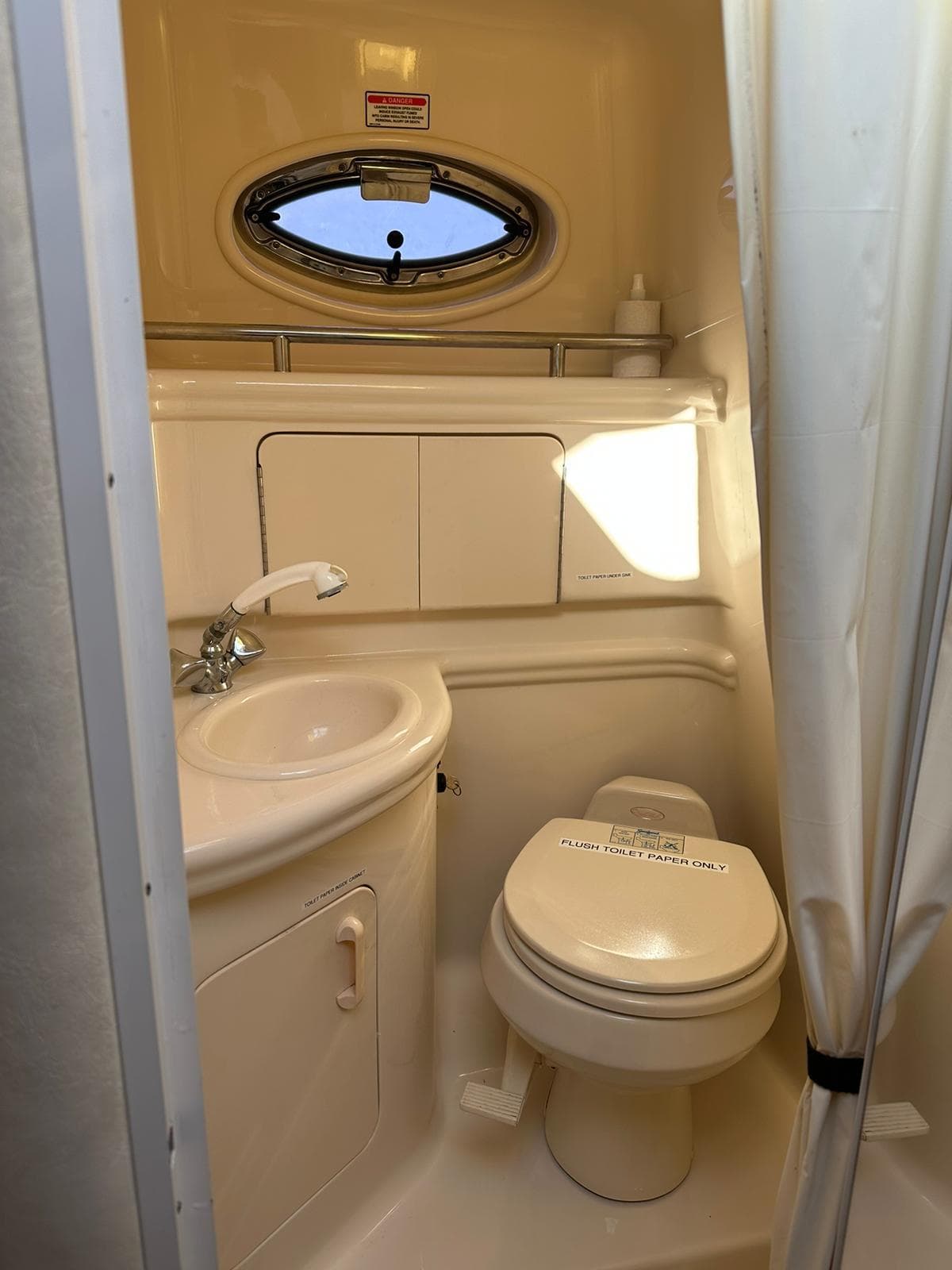 2005 Sea Ray 280 Sundancer bathroom with sink, toilet, and porthole window.