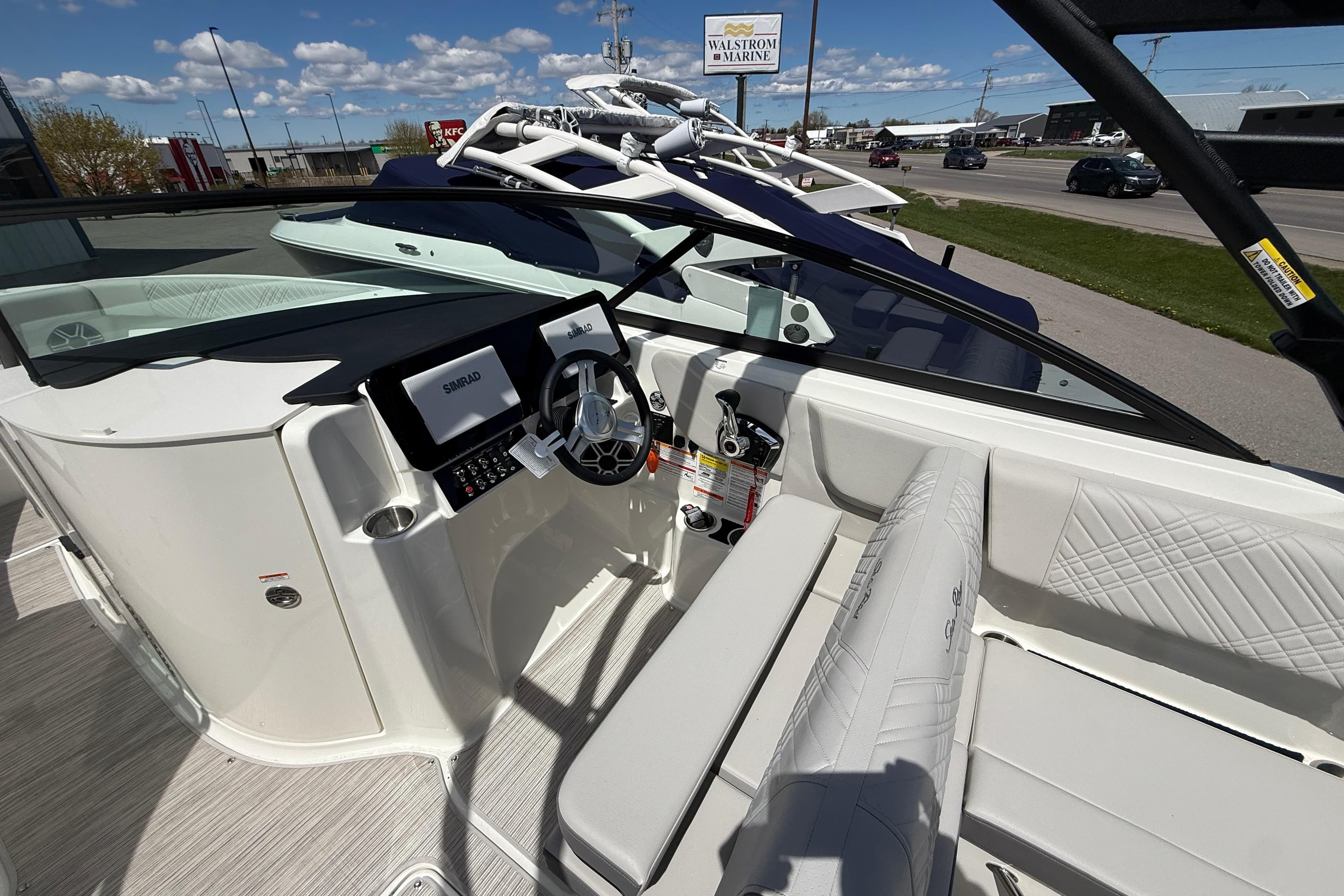 2026 Sea Ray SDX 250 boat interior with steering wheel and seating, under clear blue sky.