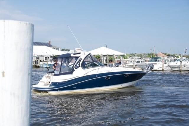 2014 Four Winns 355V boat cruising in a marina on a sunny day.