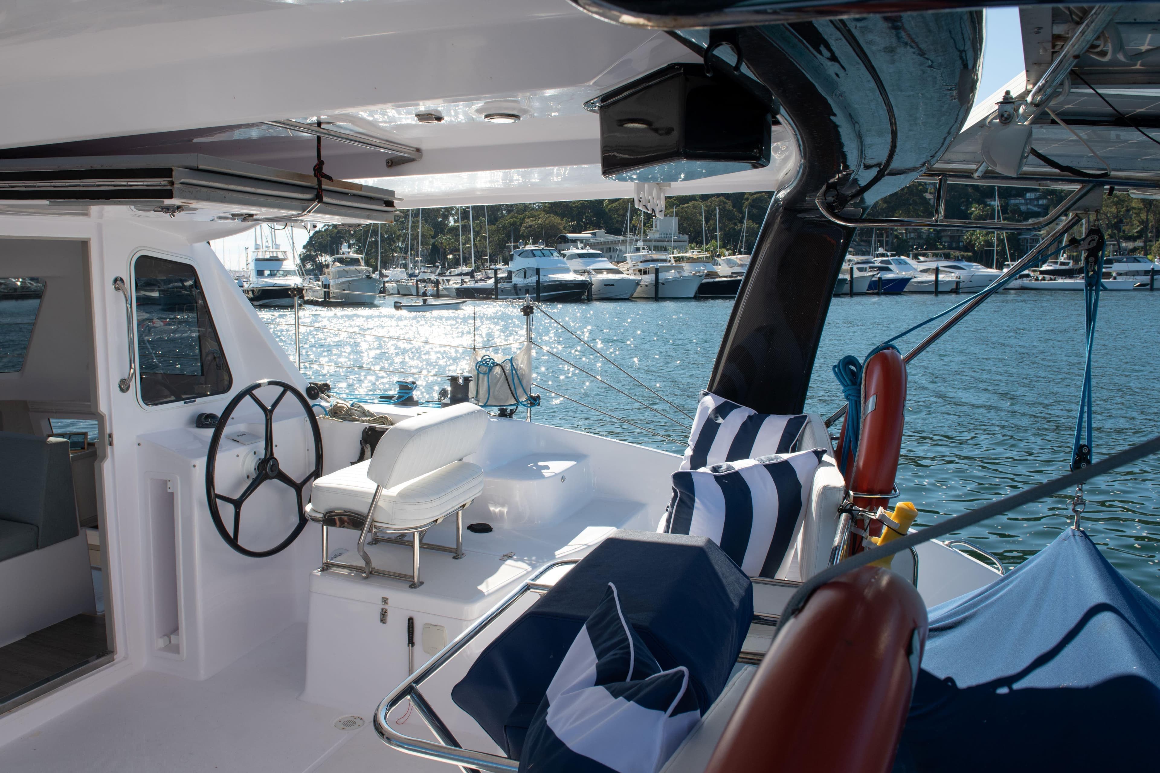 2019 Seawind 1190 catamaran interior with marina view, featuring helm and striped cushions.