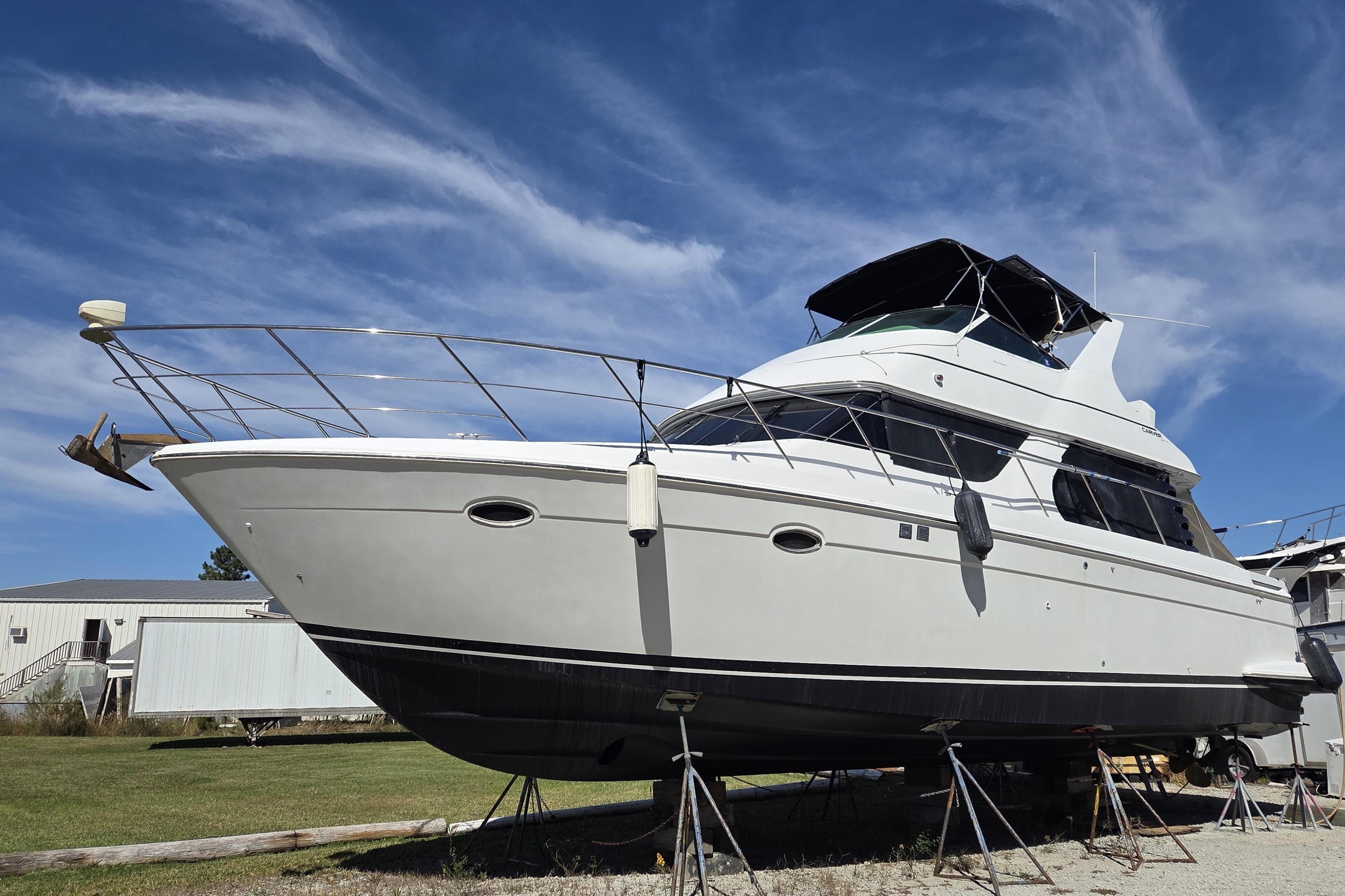 2000 Carver 450 Voyager Pilothouse yacht on stands under a clear blue sky.