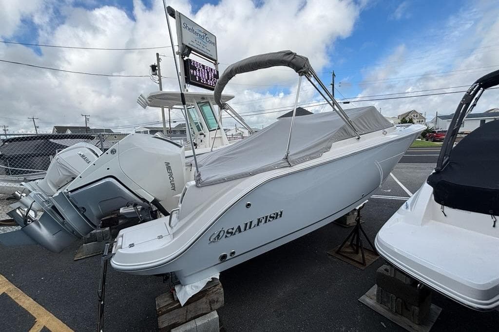 2026 Sailfish 236 DC boat with cover, parked on a lot under a cloudy sky.
