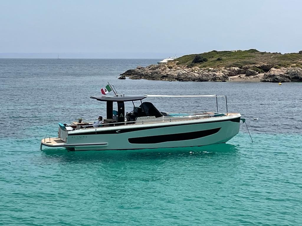 Italyure 38 boat, 2022 model, anchored in clear turquoise waters near a rocky island.