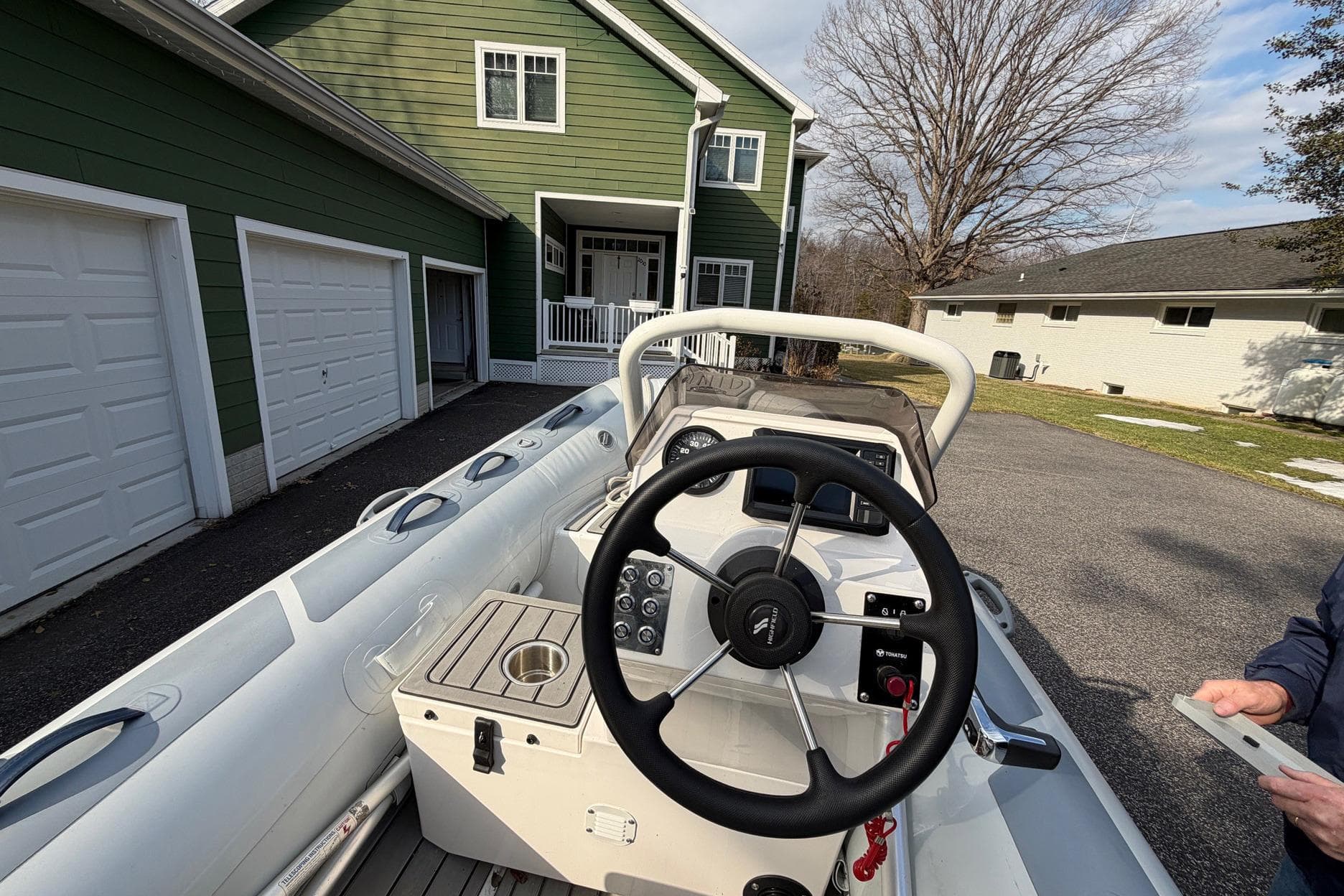 2004 Sea Ray 500 Sundancer boat steering wheel in driveway near green house.
