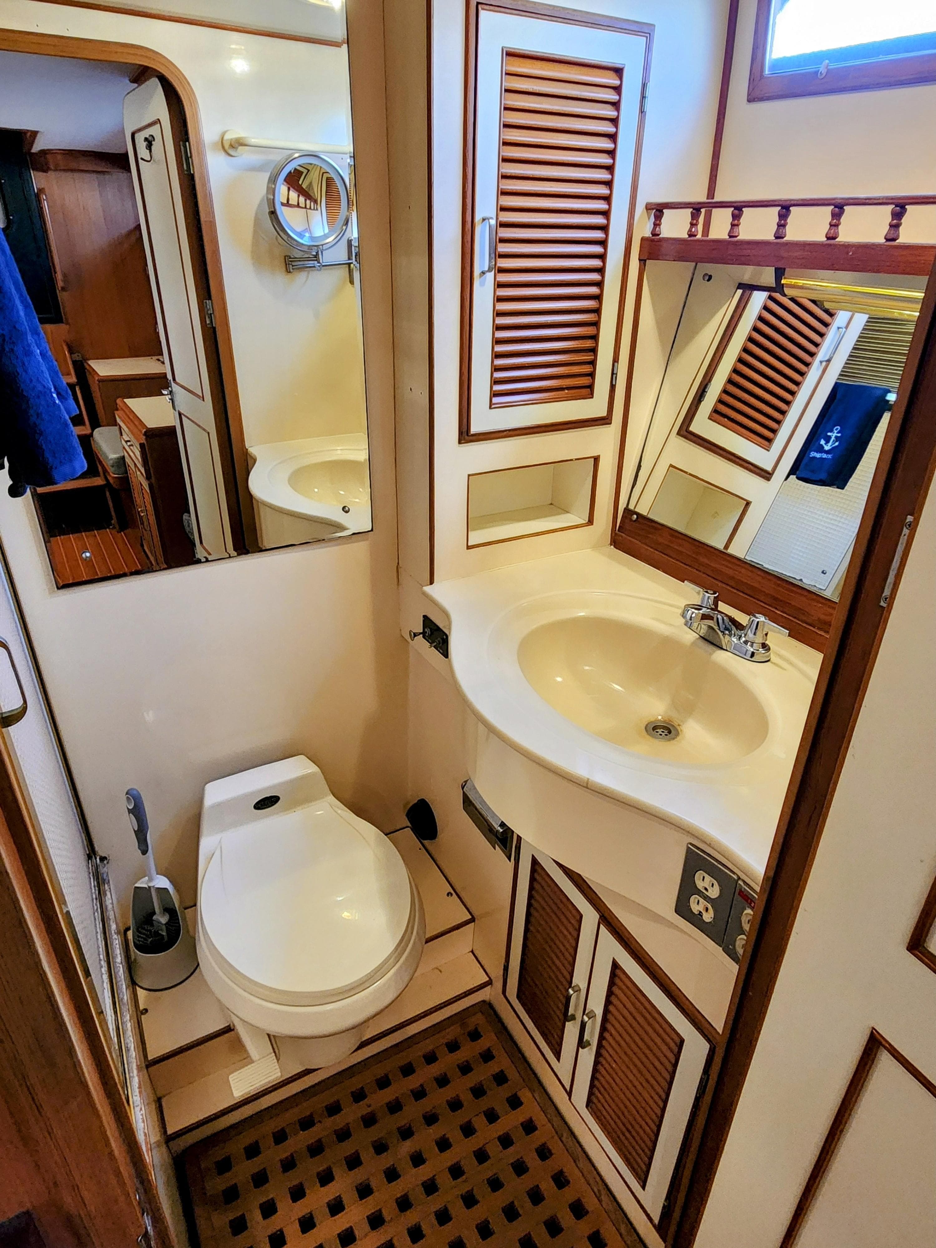 1987 Hi-Star Yacht Fisher 55 bathroom with sink, toilet, and wooden cabinetry.