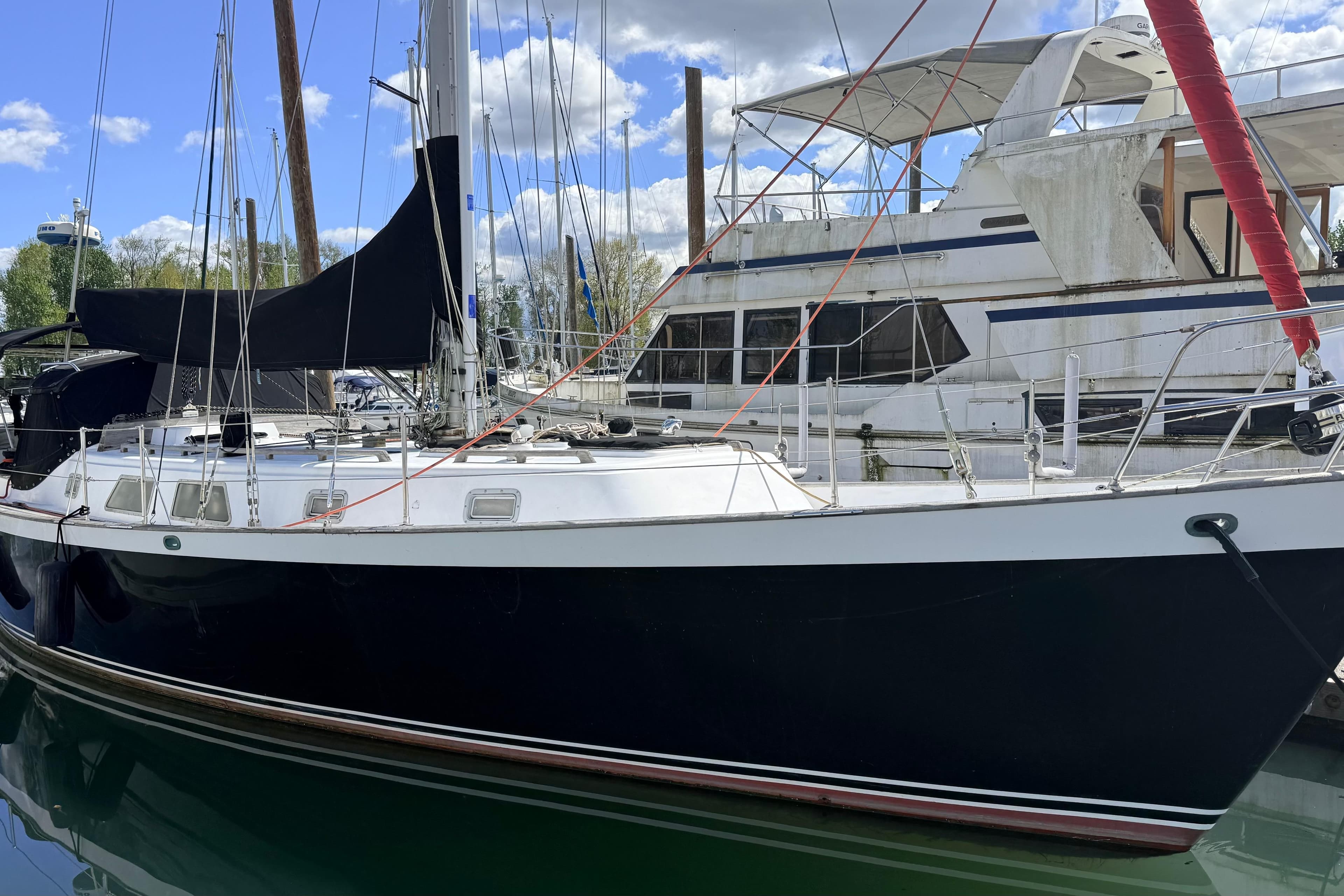 1983 Tanton 44 sailboat docked at marina, clear sky, calm water.