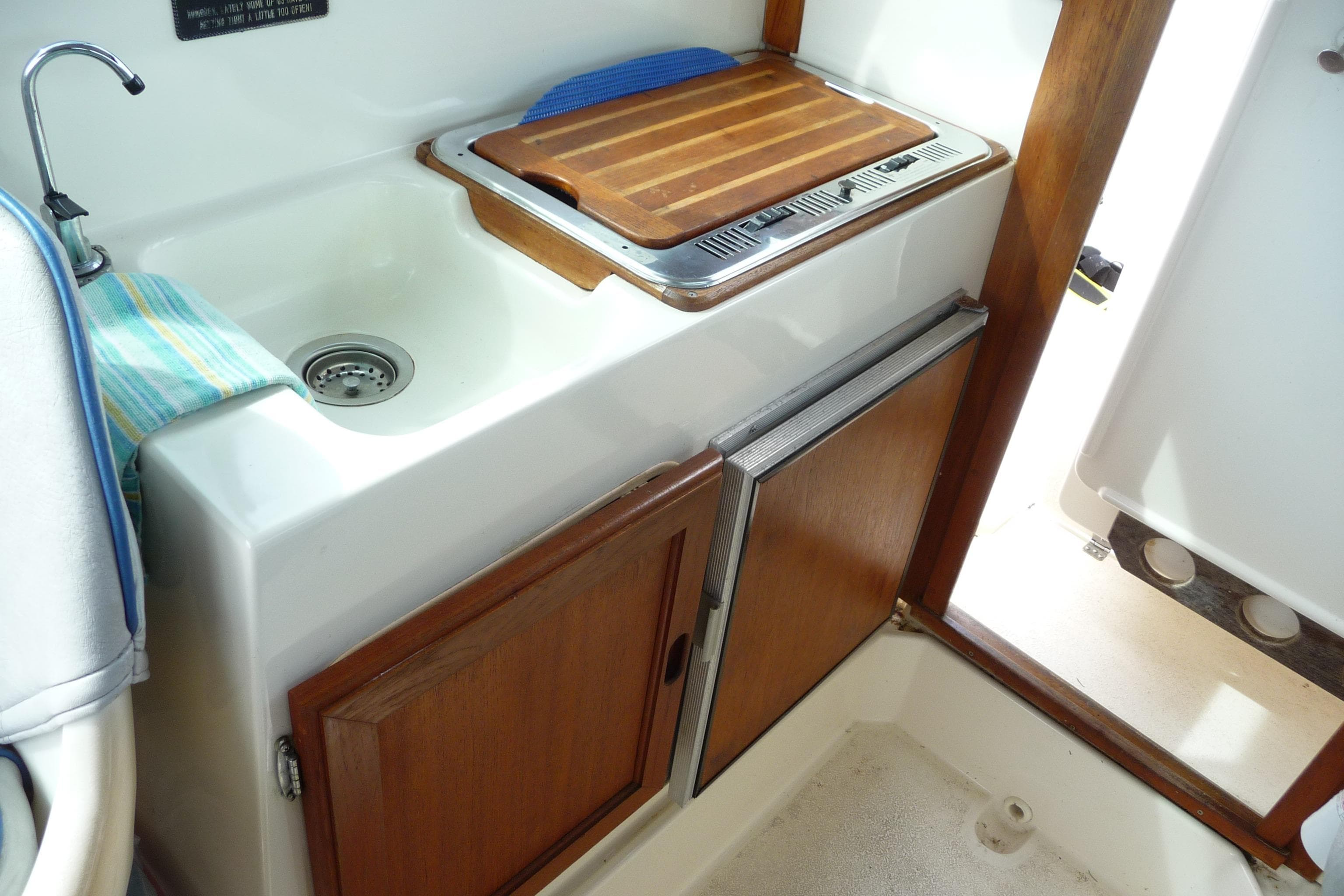 1988 Bayliner 2102 Trophy boat interior with sink, cutting board, and wooden cabinetry.