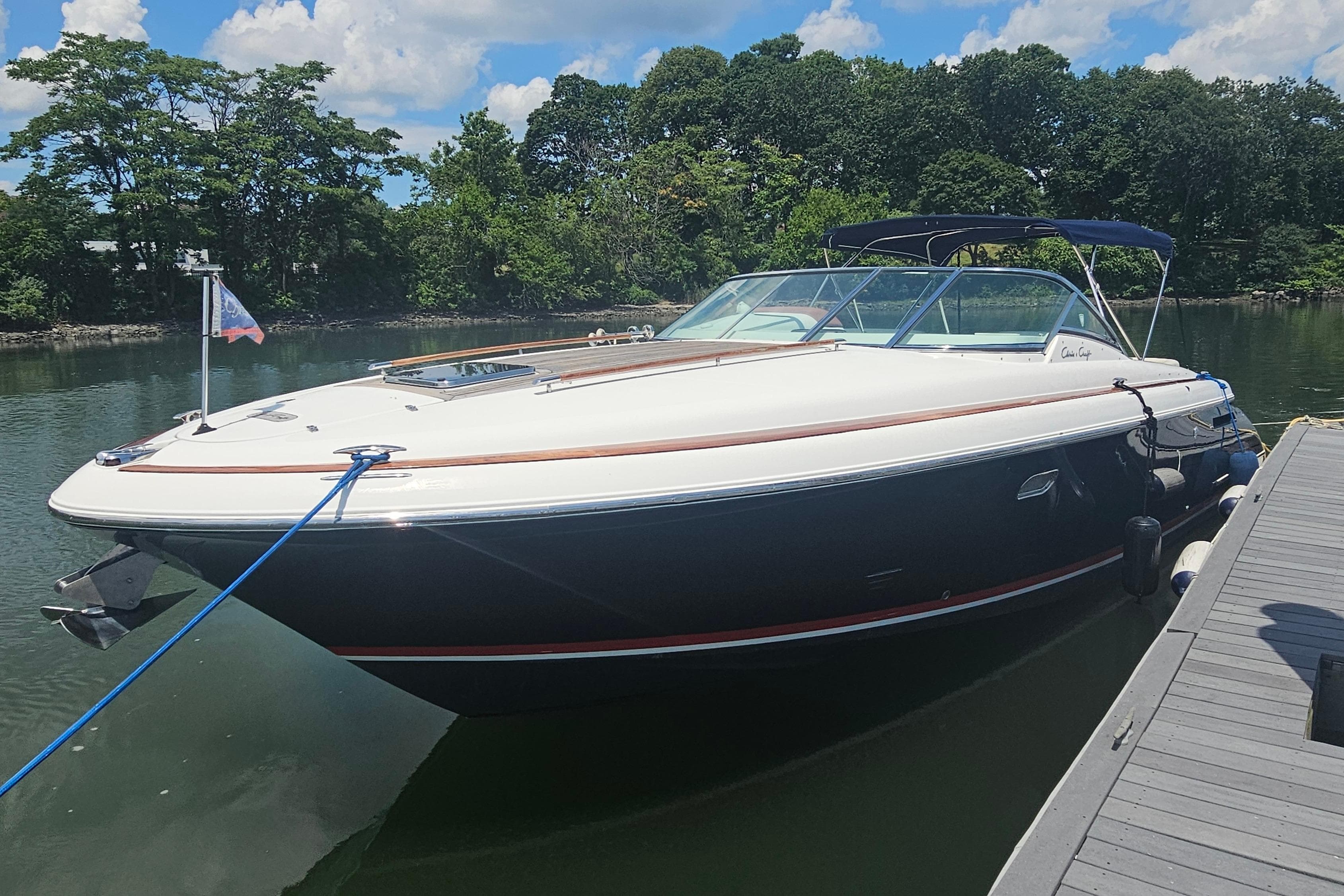 2006 Chris-Craft Corsair 36 boat docked on a sunny day with lush greenery.