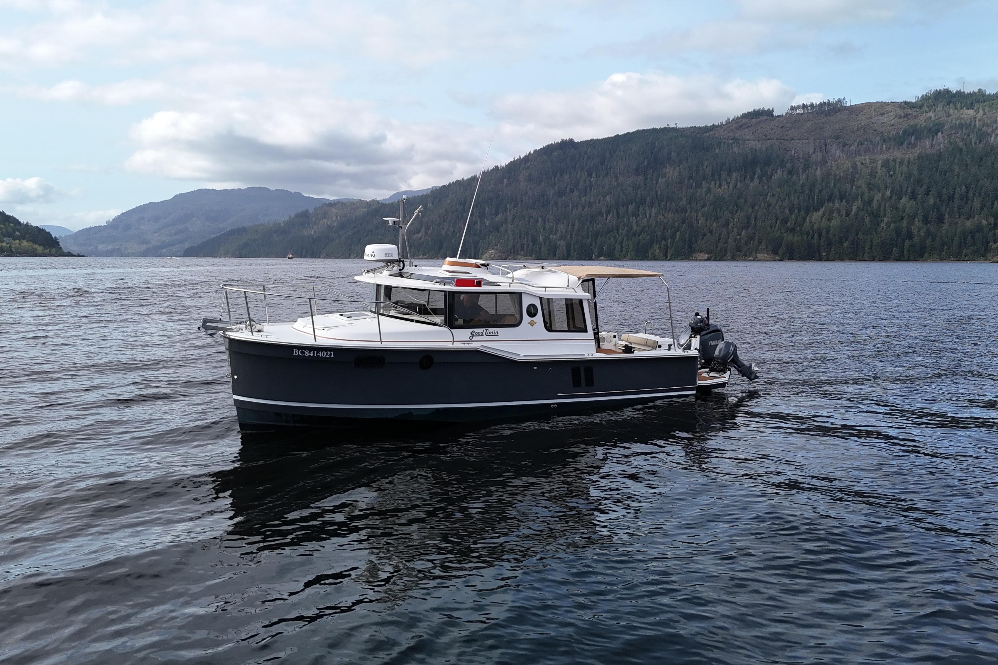 2022 Ranger Tugs R-27 boat on a scenic lake with forested hills.