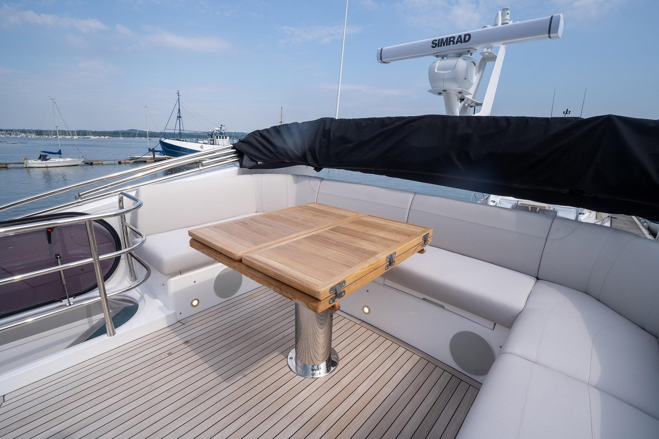 Flybridge seating area on 2024 Sunseeker Manhattan 55 yacht with wooden table and ocean view.