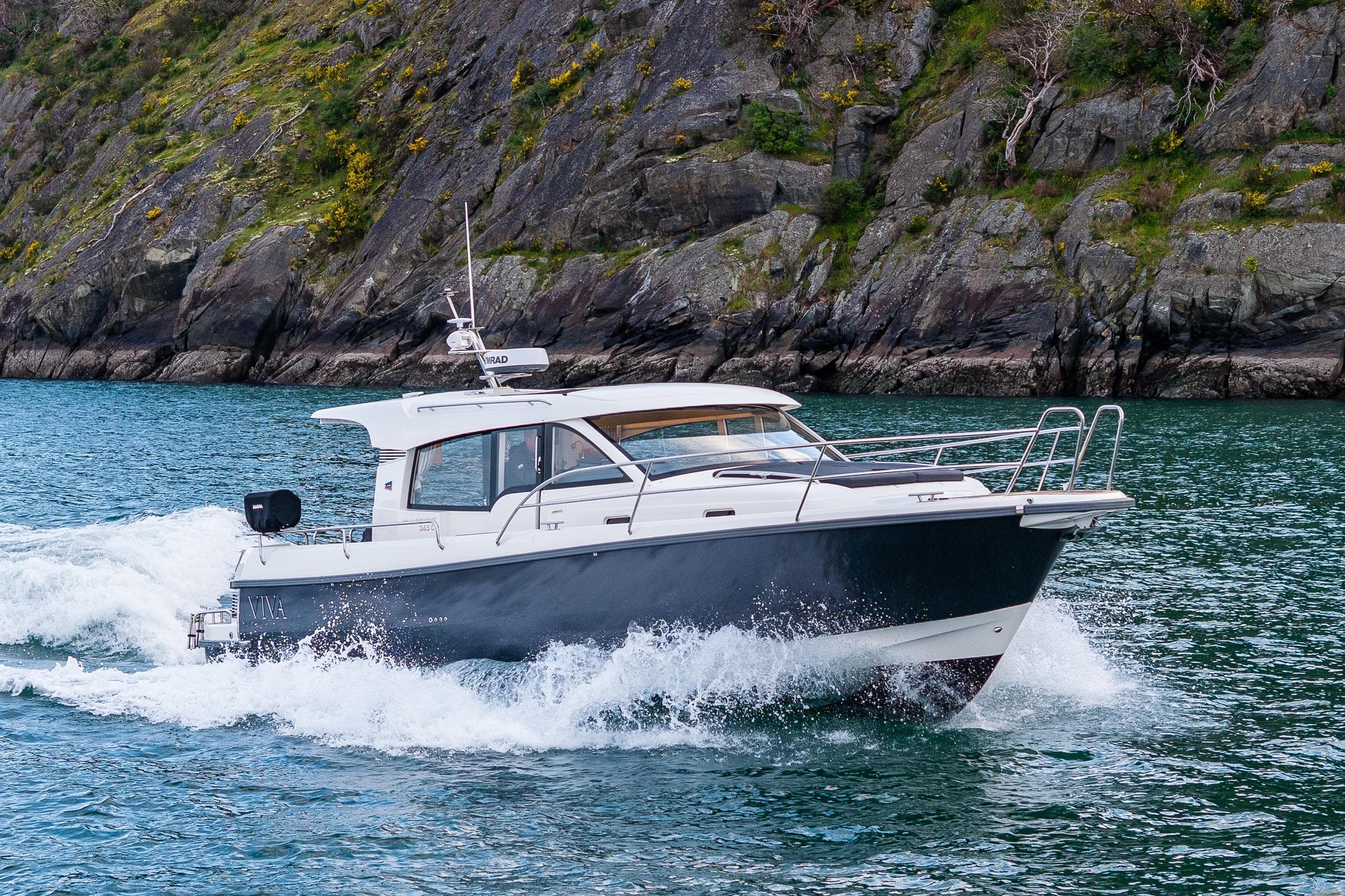 Nimbus 365 Coupe 2022 cruising on water near rocky shoreline.