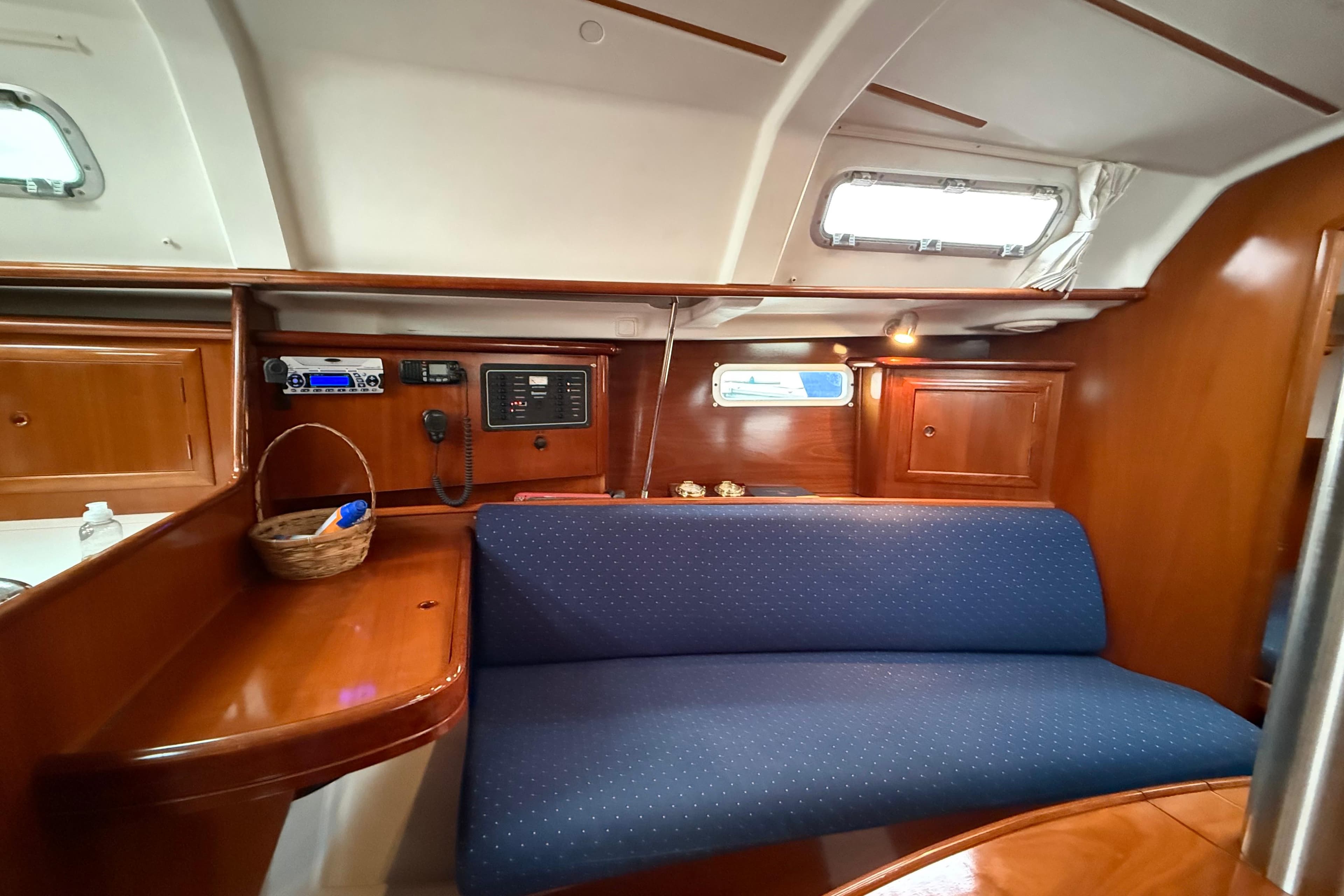 Interior of 2005 Beneteau 331 sailboat with blue seating and wooden cabinetry.