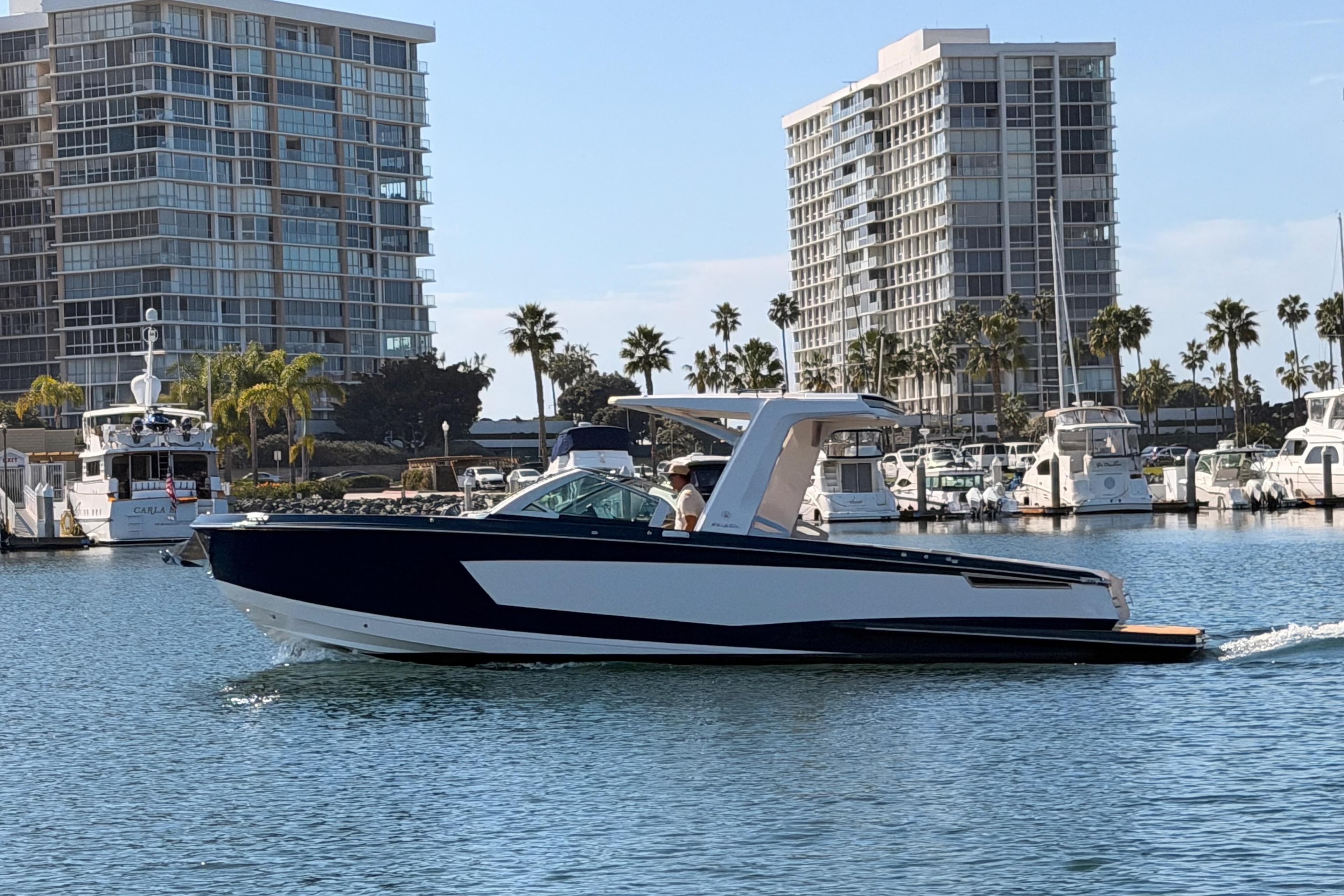 2022 Aviara AV32 I/O boat cruising in a marina with modern buildings in the background.