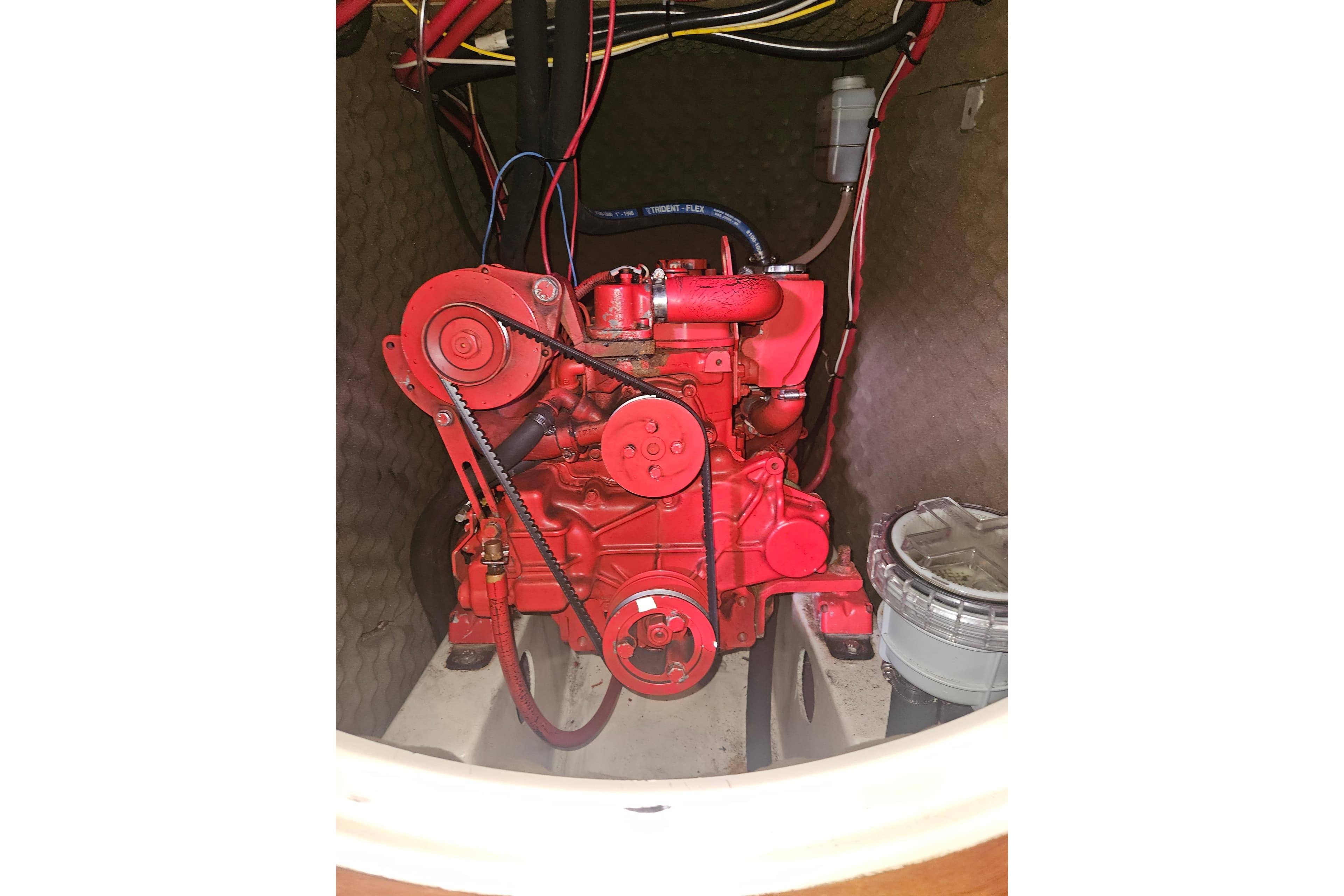 Red engine inside a 1998 Beneteau 381 sailboat, showcasing mechanical components.