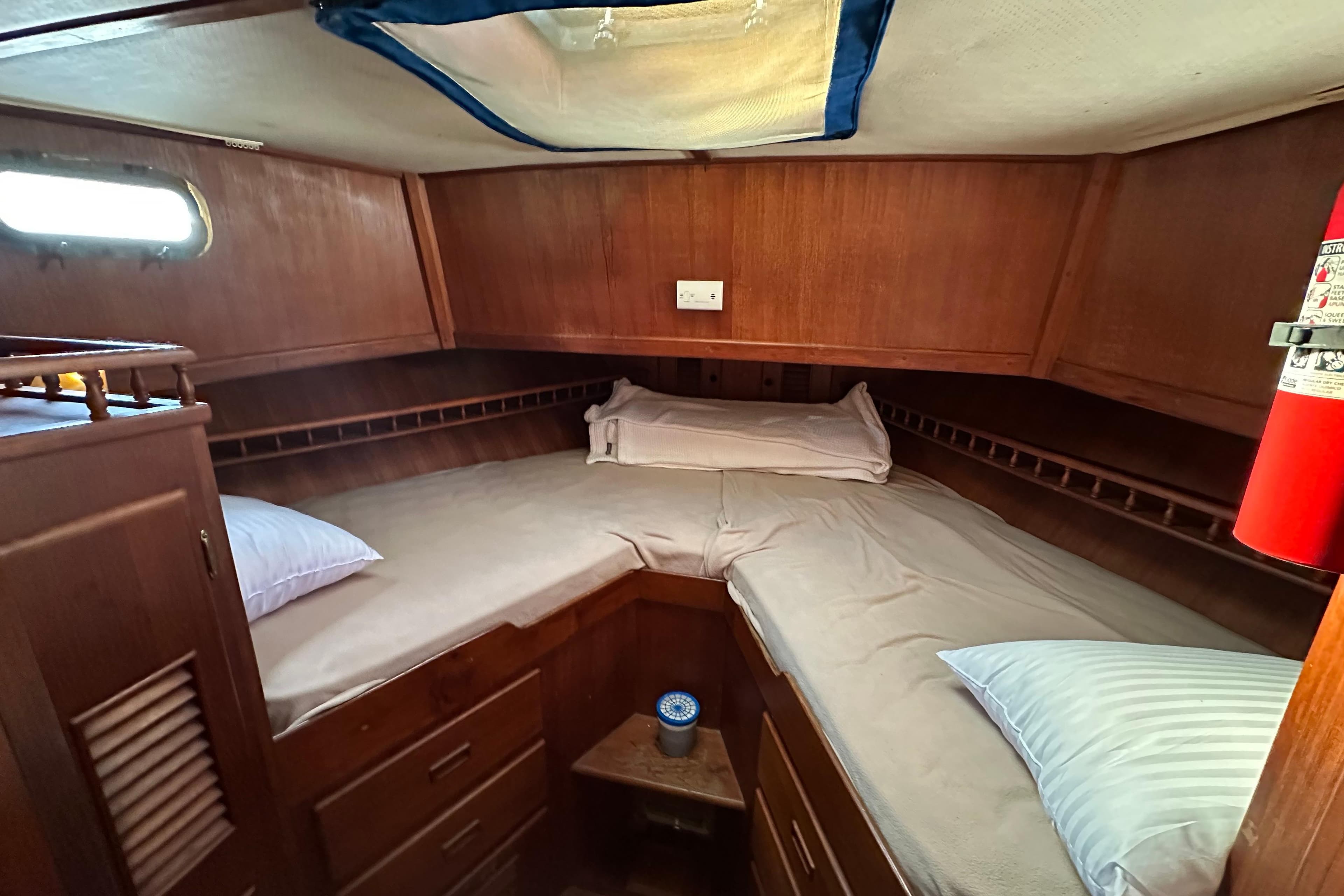 1979 Marine Trader 38DC cabin with wooden interior, bed, and fire extinguisher.