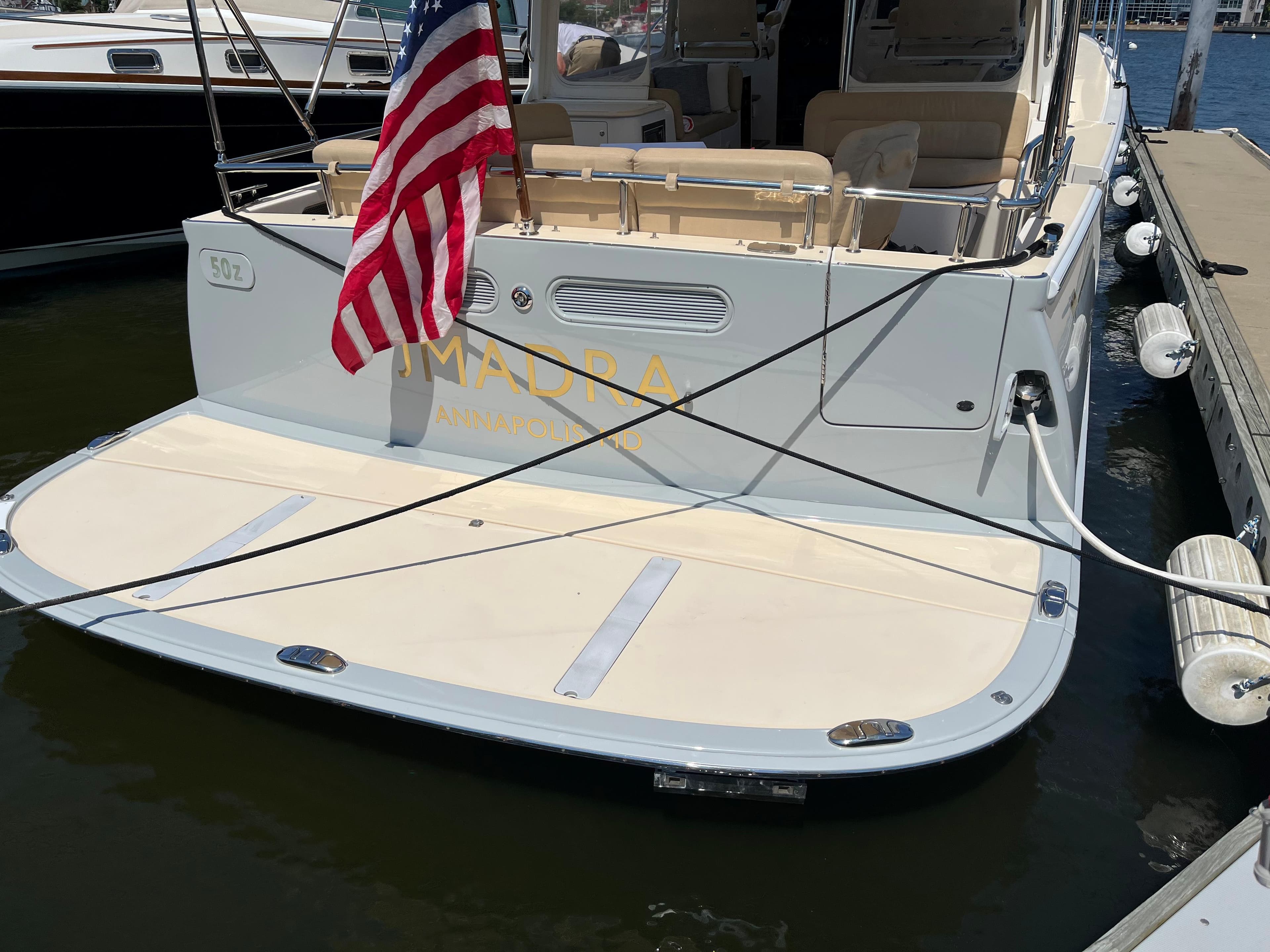 Stern view of a 2016 MJM 50z yacht docked, featuring an American flag.