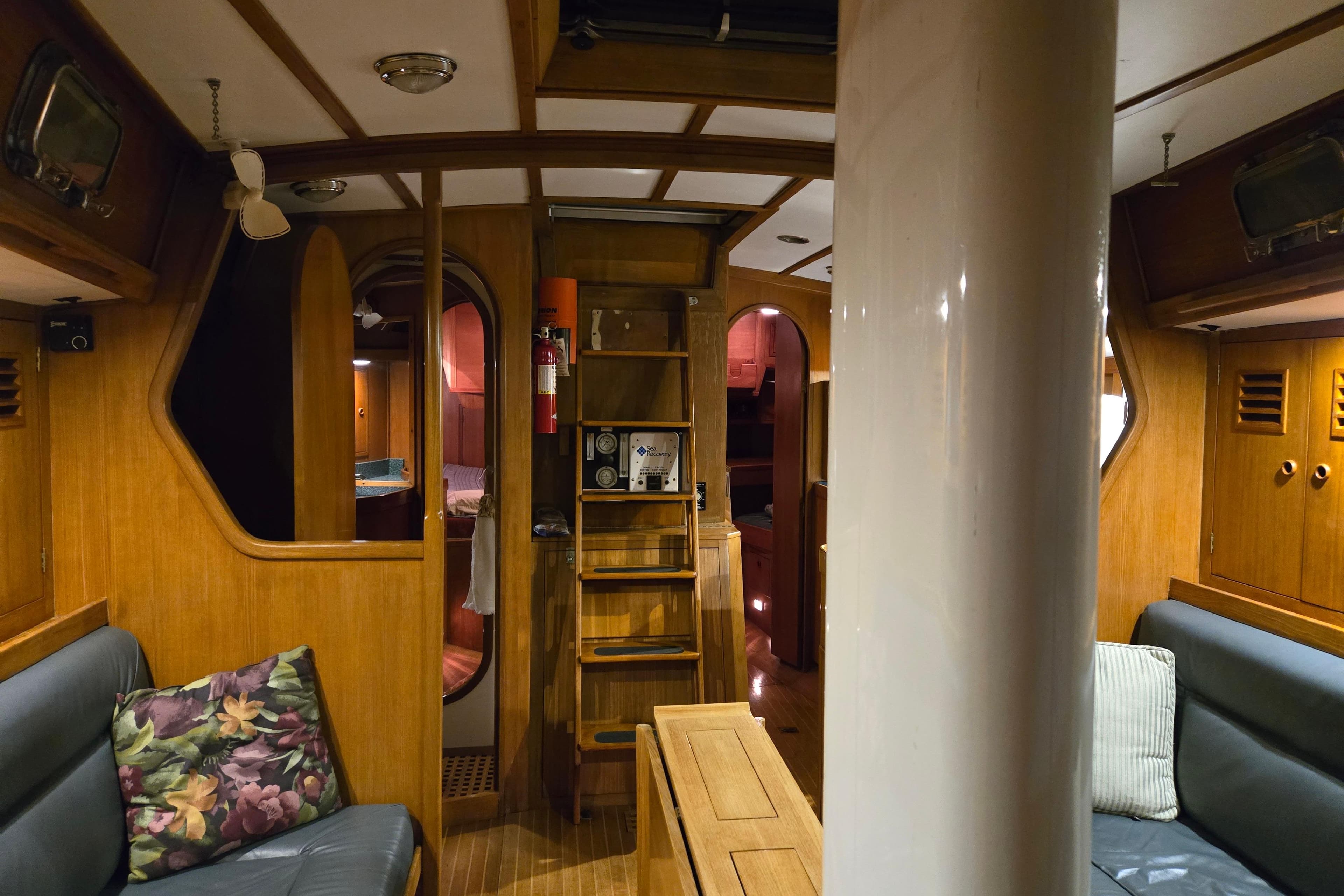 Interior of 1986 Cambria 46 yacht with wooden furnishings and cozy seating area.