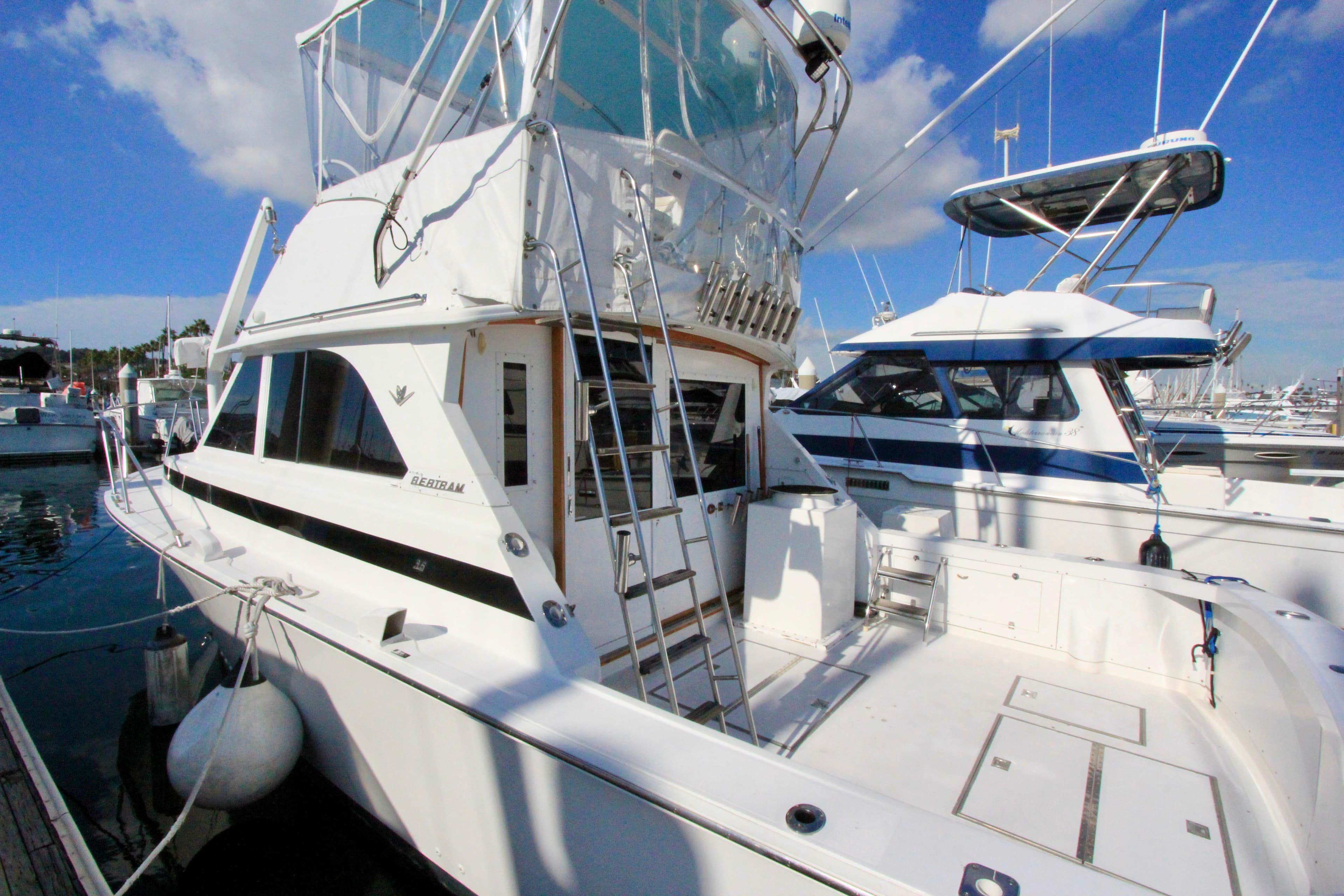 1982 Bertram 35 Flybridge yacht docked at marina under clear blue sky.