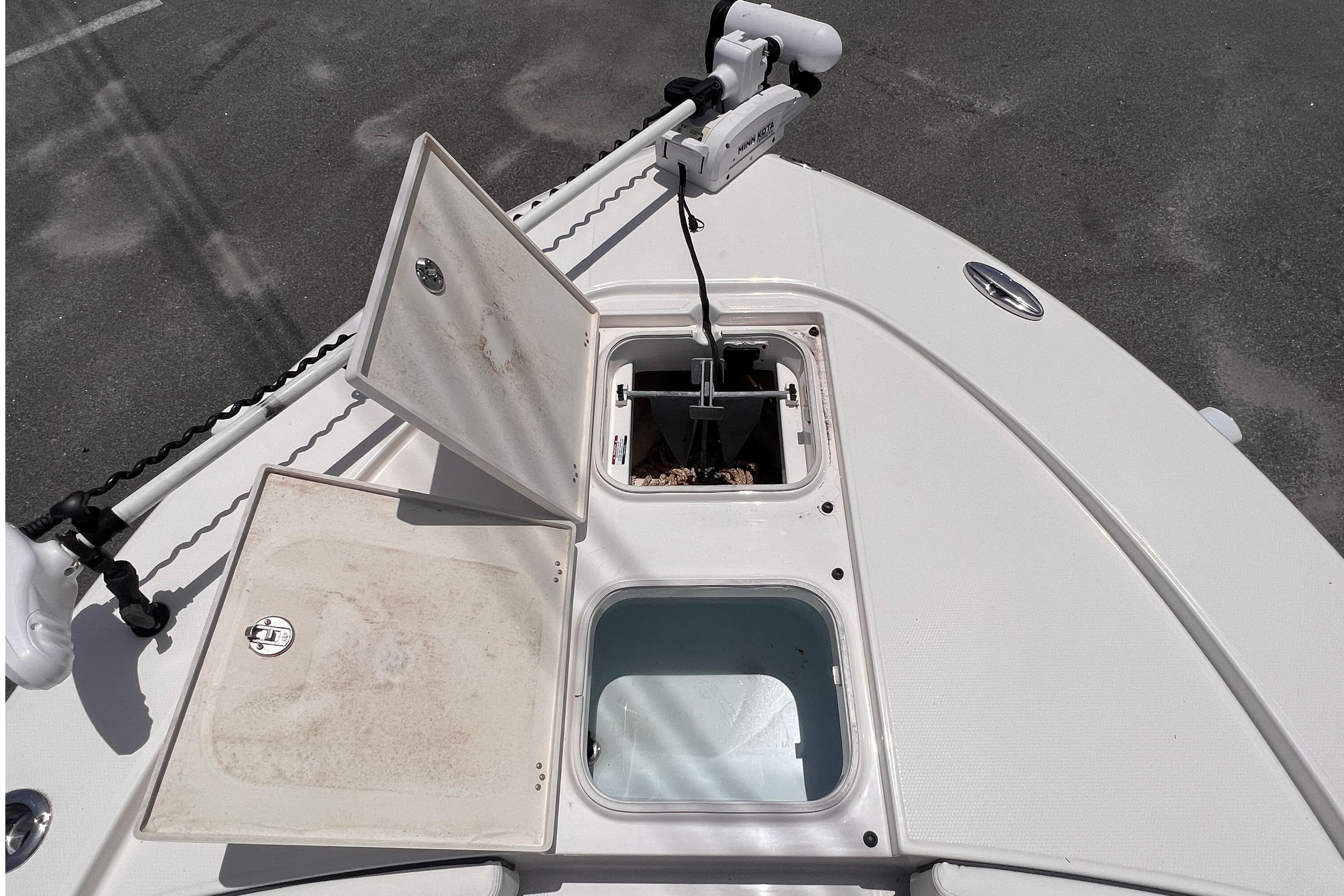 2022 Robalo 246 Cayman boat deck with open storage compartments and trolling motor.