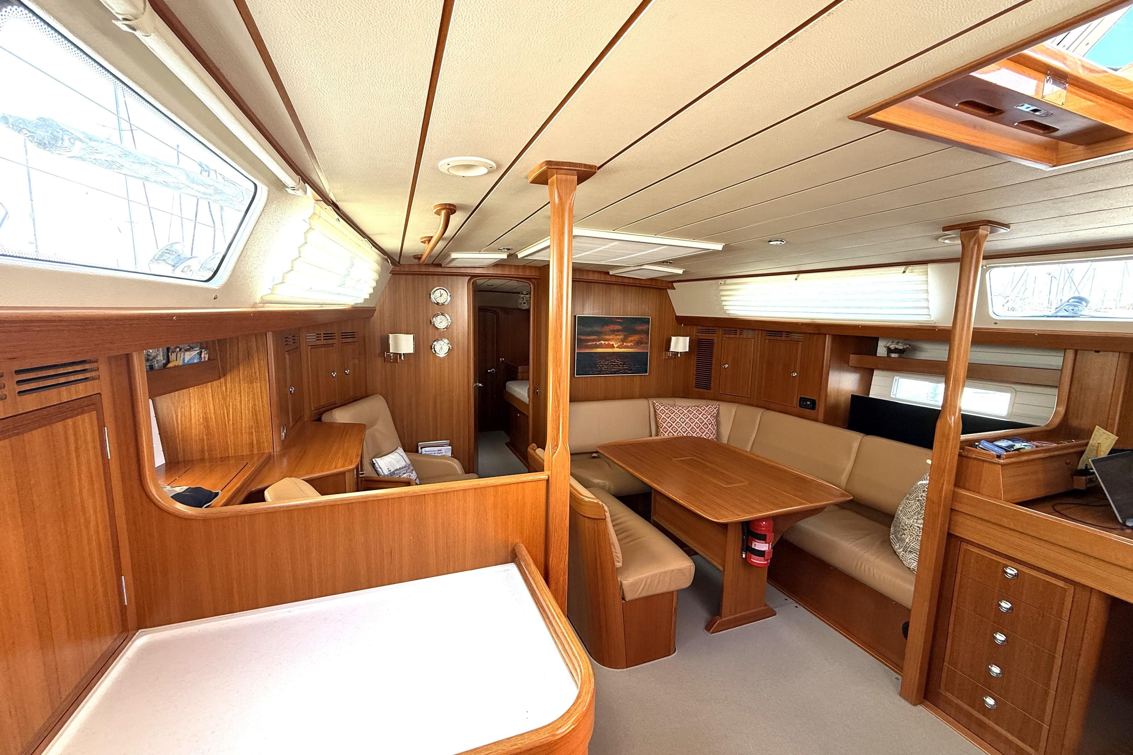 Interior of 2016 Hallberg-Rassy 55 yacht, featuring elegant wood finish and spacious seating area.