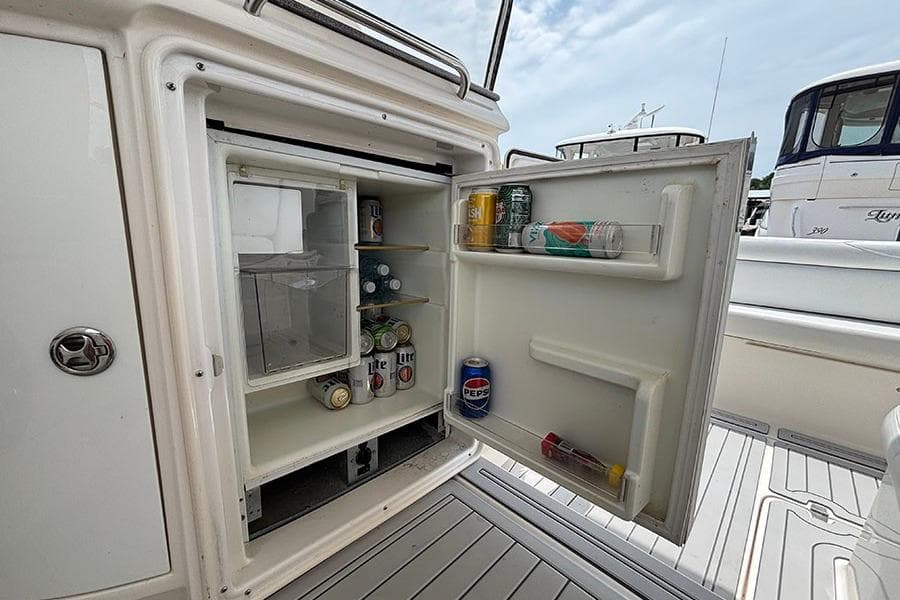Open mini fridge on 2005 Regal Commodore 4260 boat, stocked with beverages.