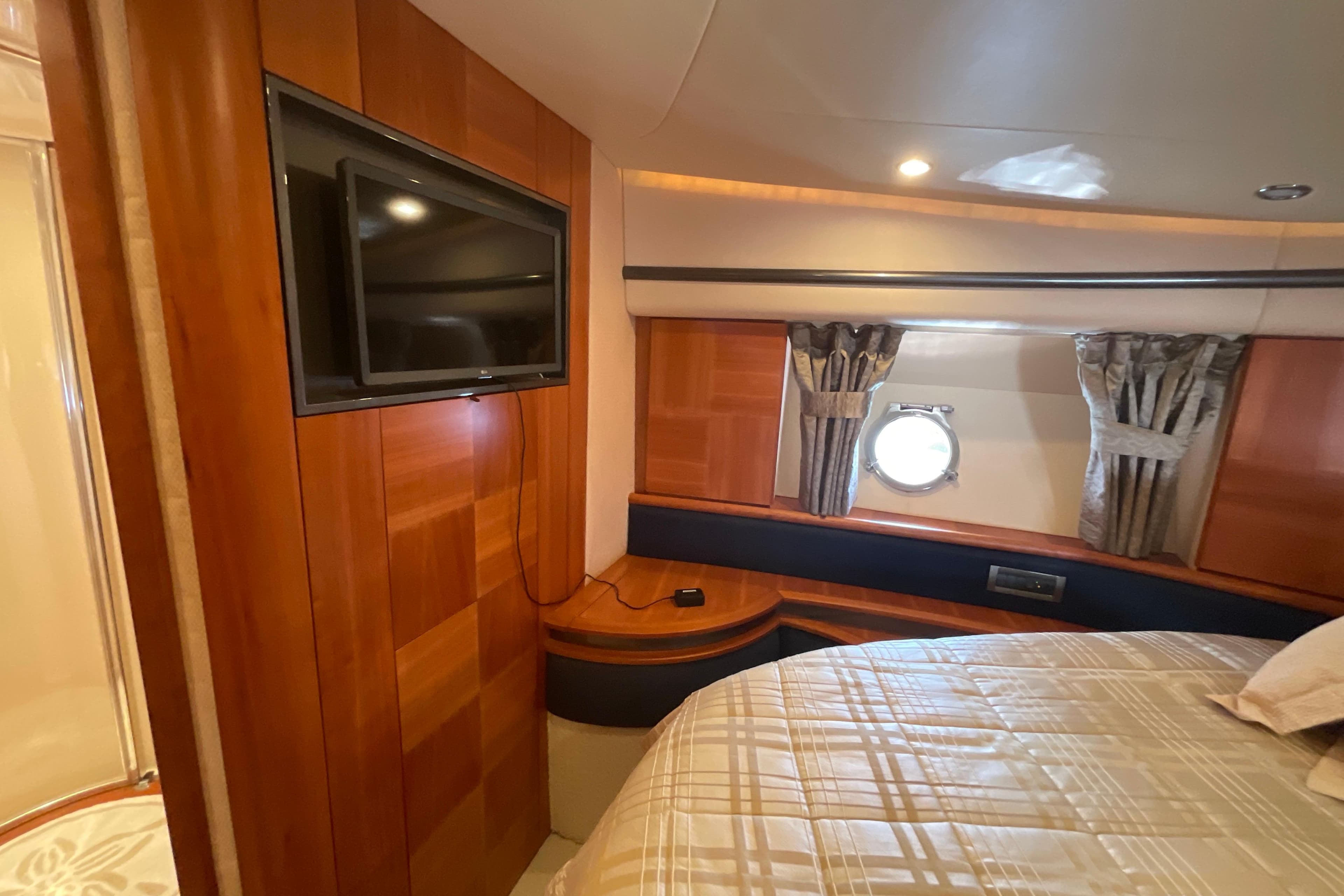 Luxurious 2005 Azimut Fly 50 yacht cabin with TV, wood paneling, and porthole window.