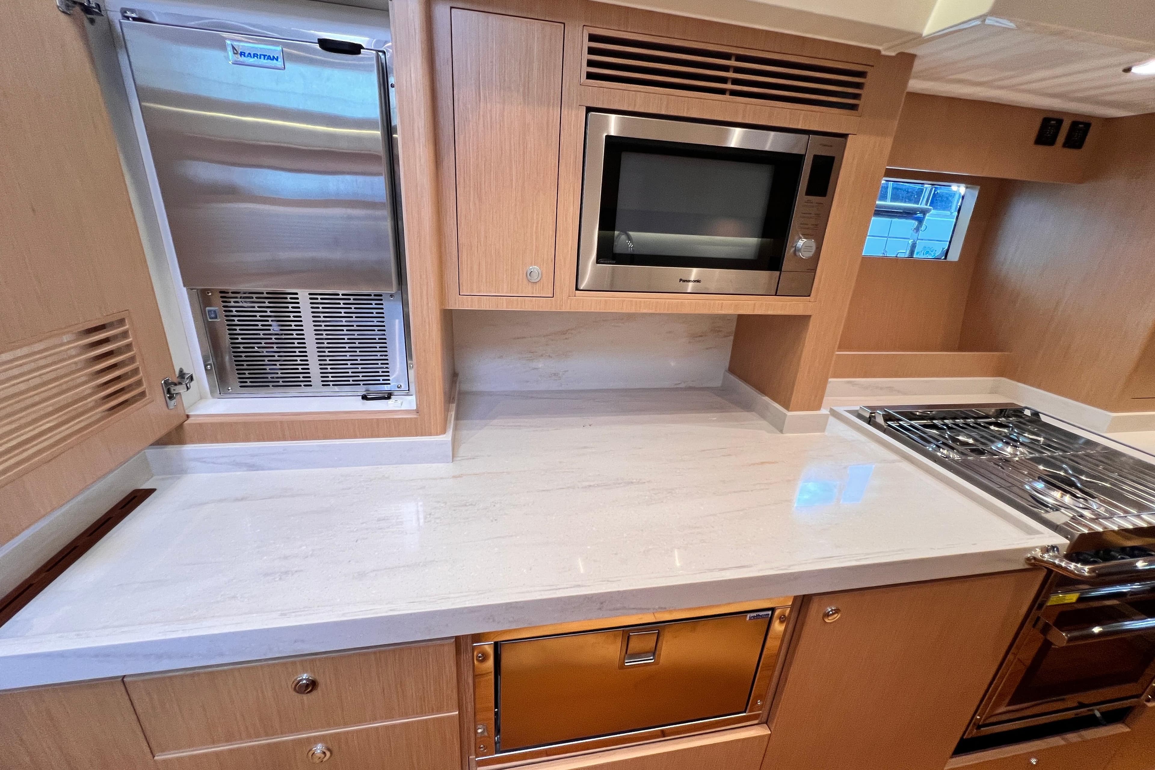Modern kitchen in 2024 Hylas H57 yacht with sleek appliances and wood cabinetry.