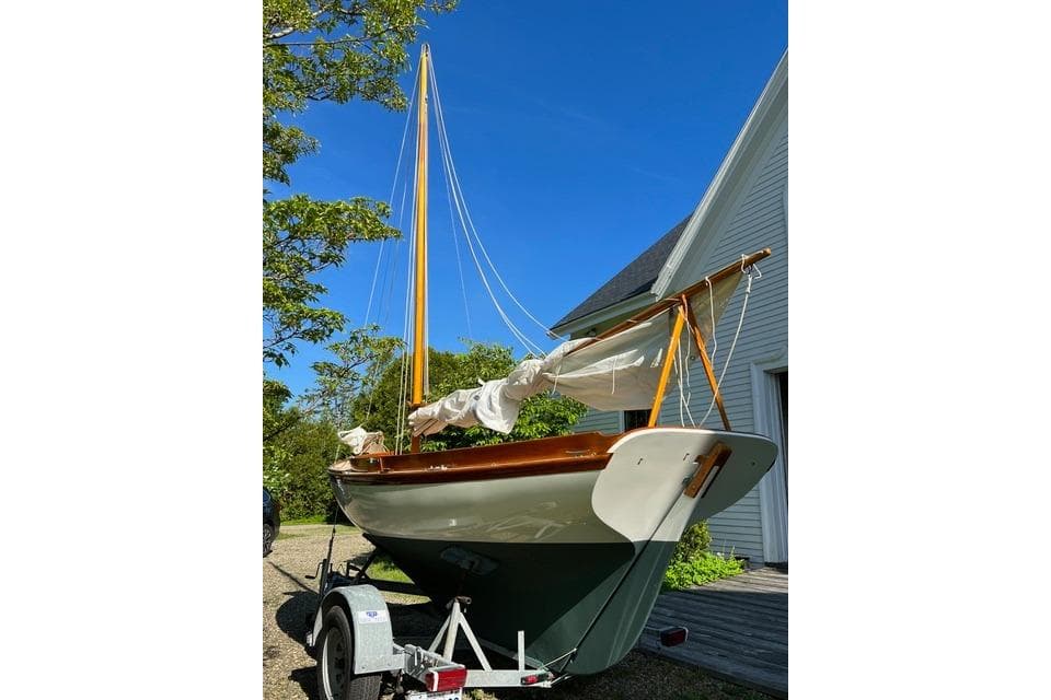 Herreshoff 12 1/2 sailboat from 2003 on a trailer, set against a clear blue sky.