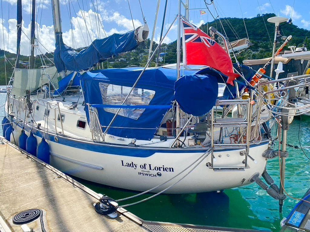 Sailboat "Lady of Lorien" docked, Pacific Seacraft 40, 2000 model, with blue covers and red flag.