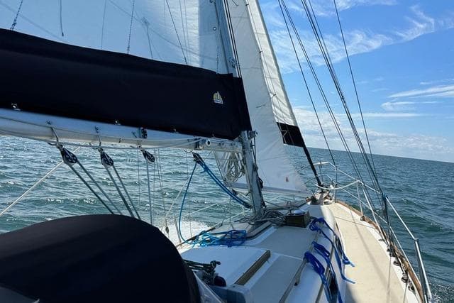 1985 Cape Dory Cutter sailboat navigating open sea under clear blue skies.